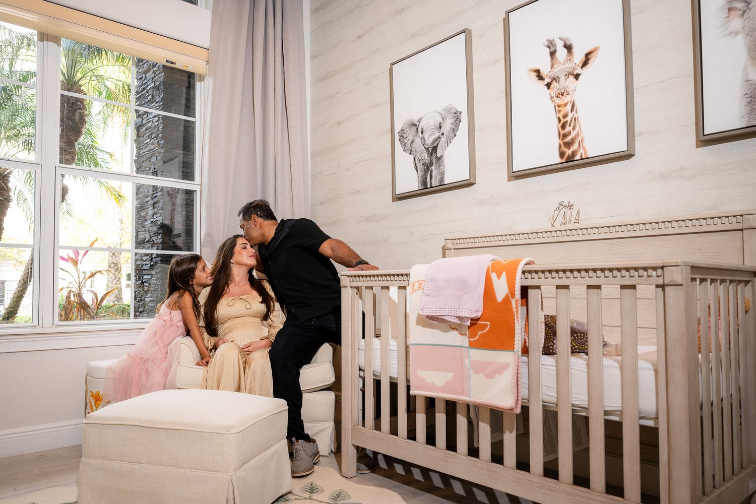 Couple sharing tender moment in nursery decorated with animal prints and grey crib.