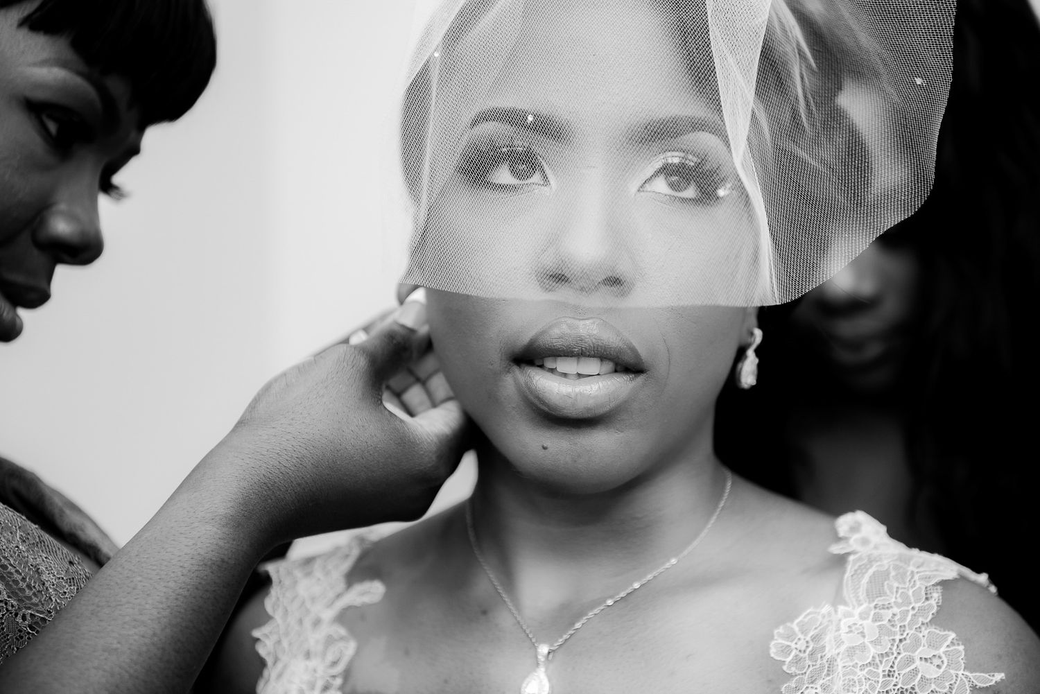 Close-up black and white portrait of a bride getting ready with bridal veil and lace dress.