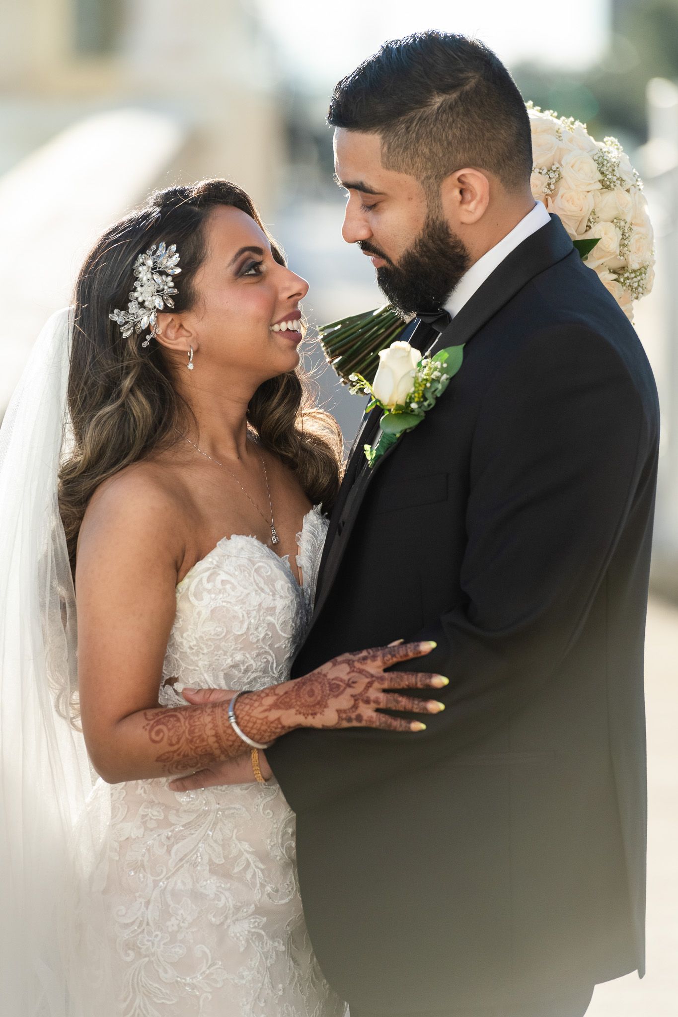 A romantic wedding portrait showing a couple gazing at each other with the bride in a lace gown.