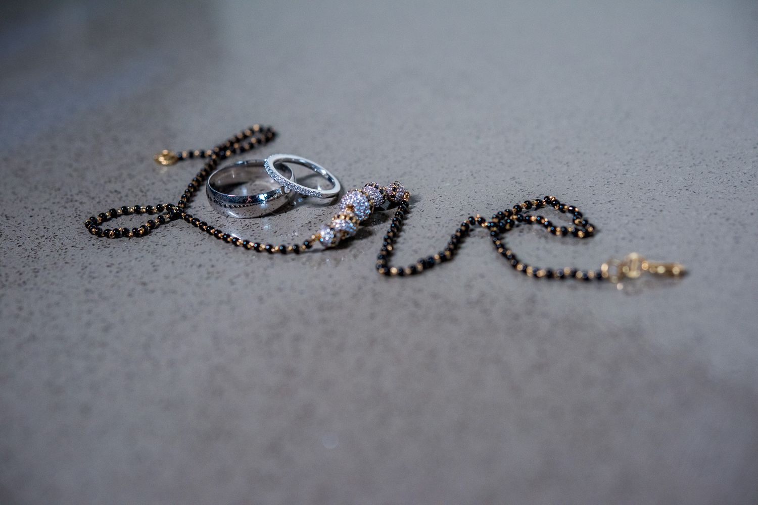 Creative wedding ring photograph spelling out 'love' with jewelry on gray surface.
