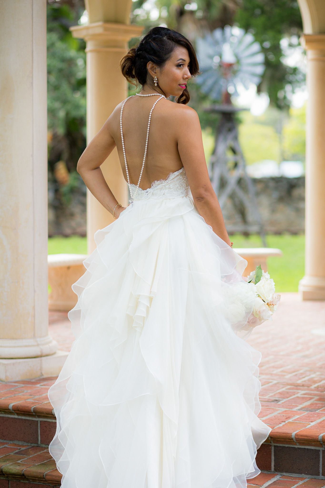 Elegant white wedding dress with strappy back detail photographed outdoors.