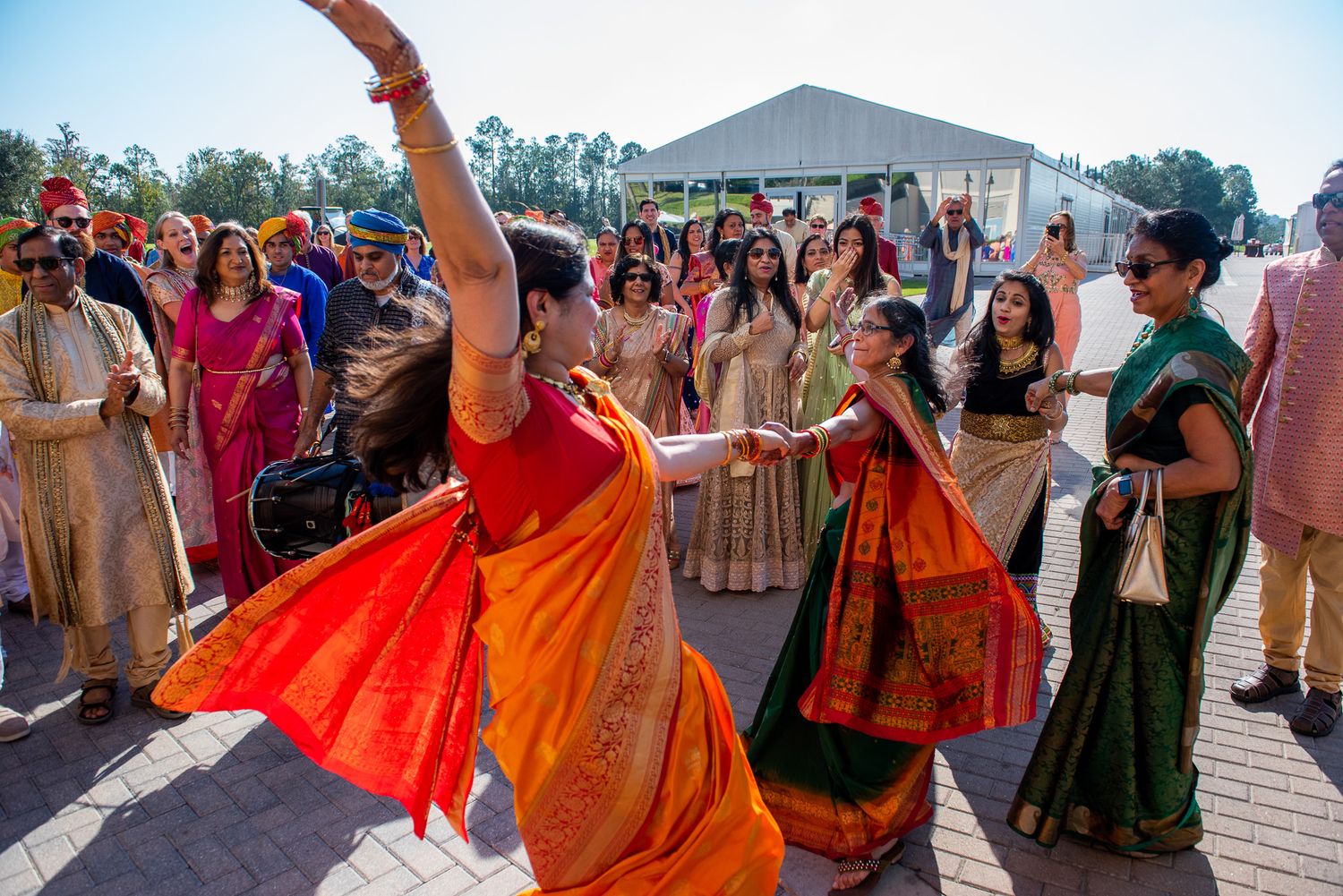 Guests dancing and celebrating at an outdoor Indian wedding ceremony.