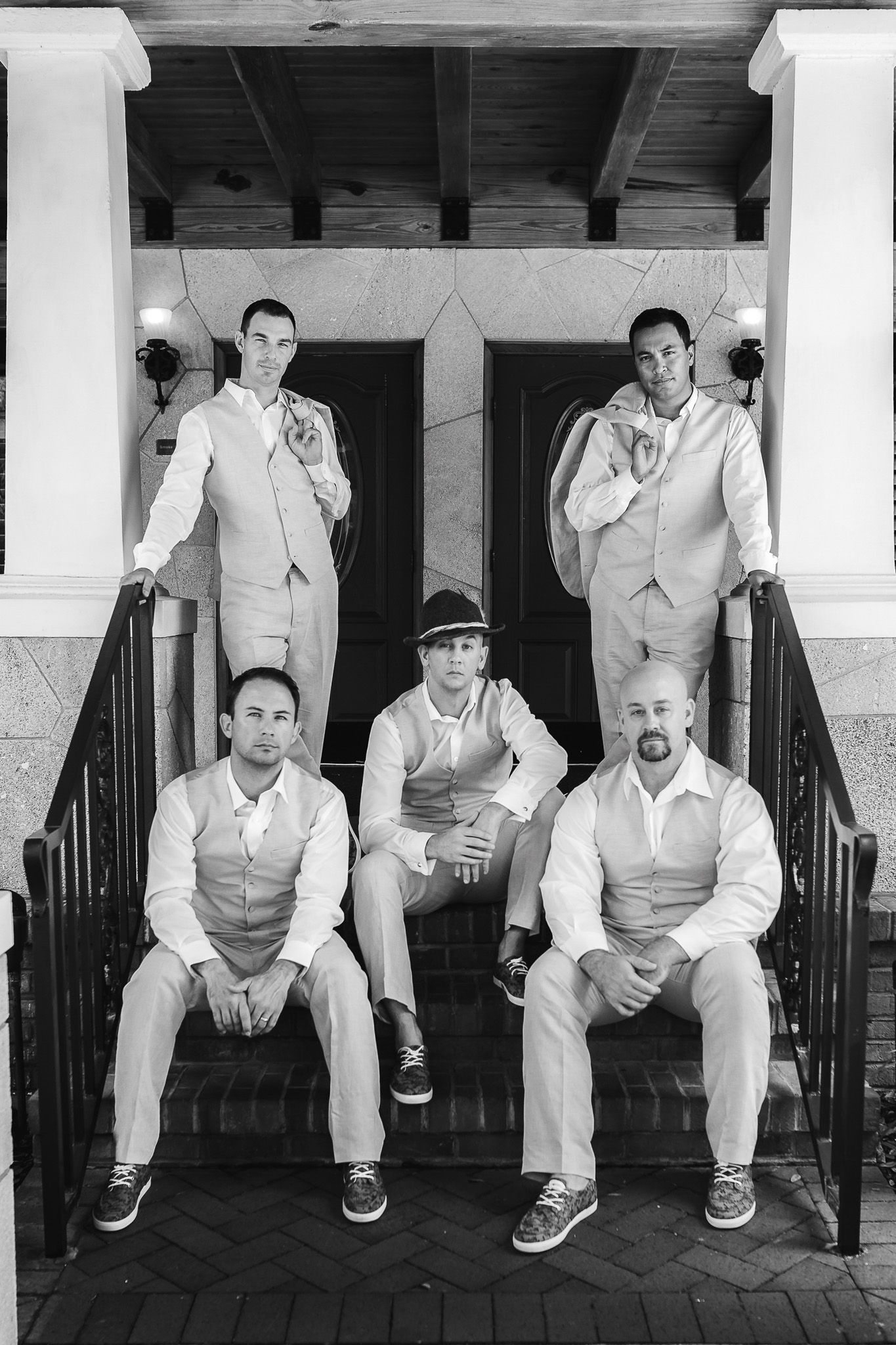 Group of groomsmen in light colored suits posing on outdoor steps in black and white.