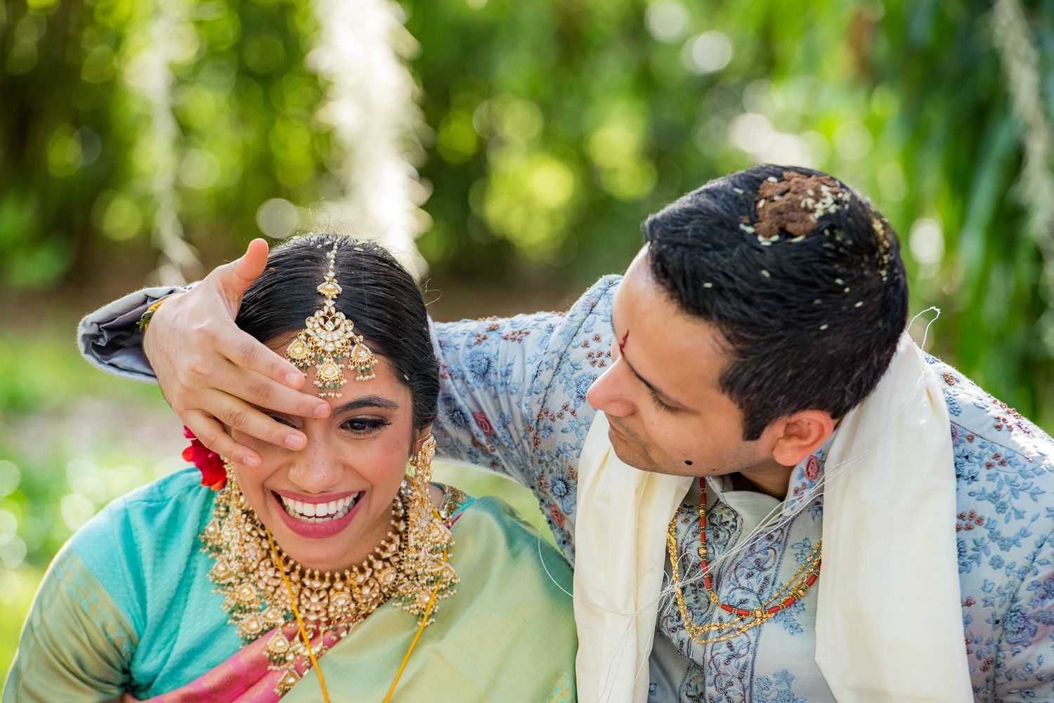Candid moment during traditional Indian wedding ceremony in outdoor garden setting.
