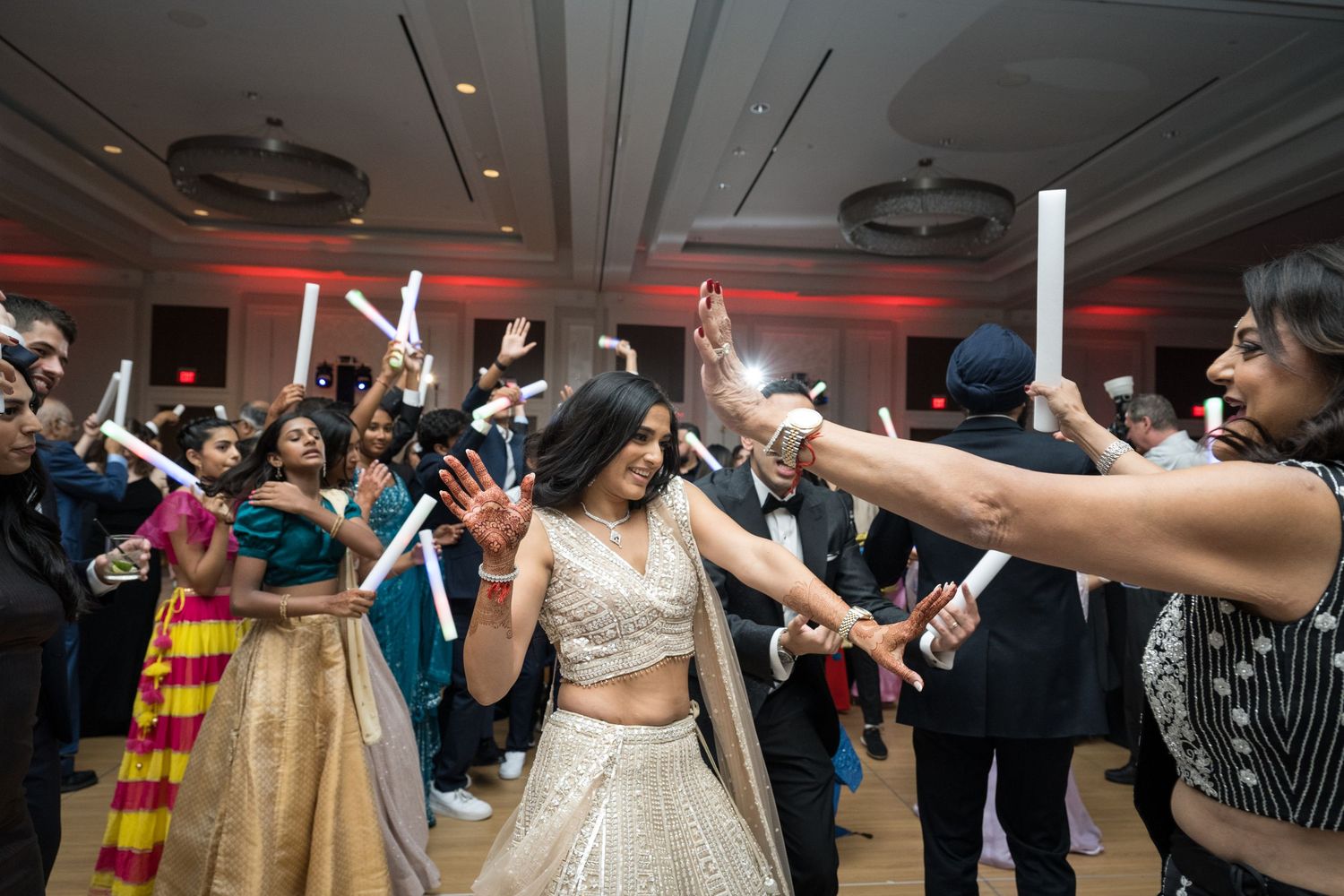 Wedding reception dance party with guests holding light sticks on dance floor.