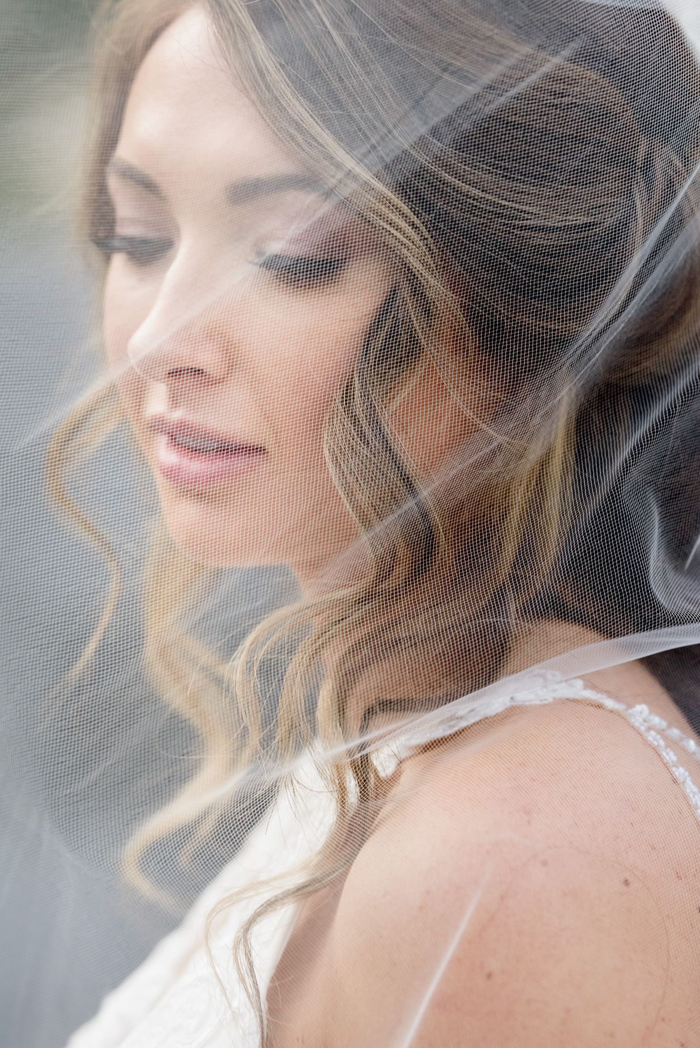Romantic closeup of bride with flowing veil and soft makeup in dreamy light.