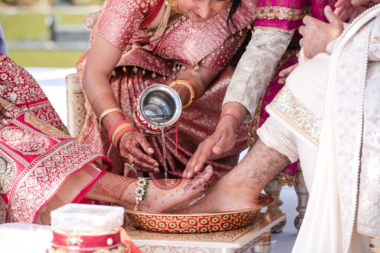 Close-up of hands performing traditional Indian wedding ritual with decorative vessels and jewelry.
