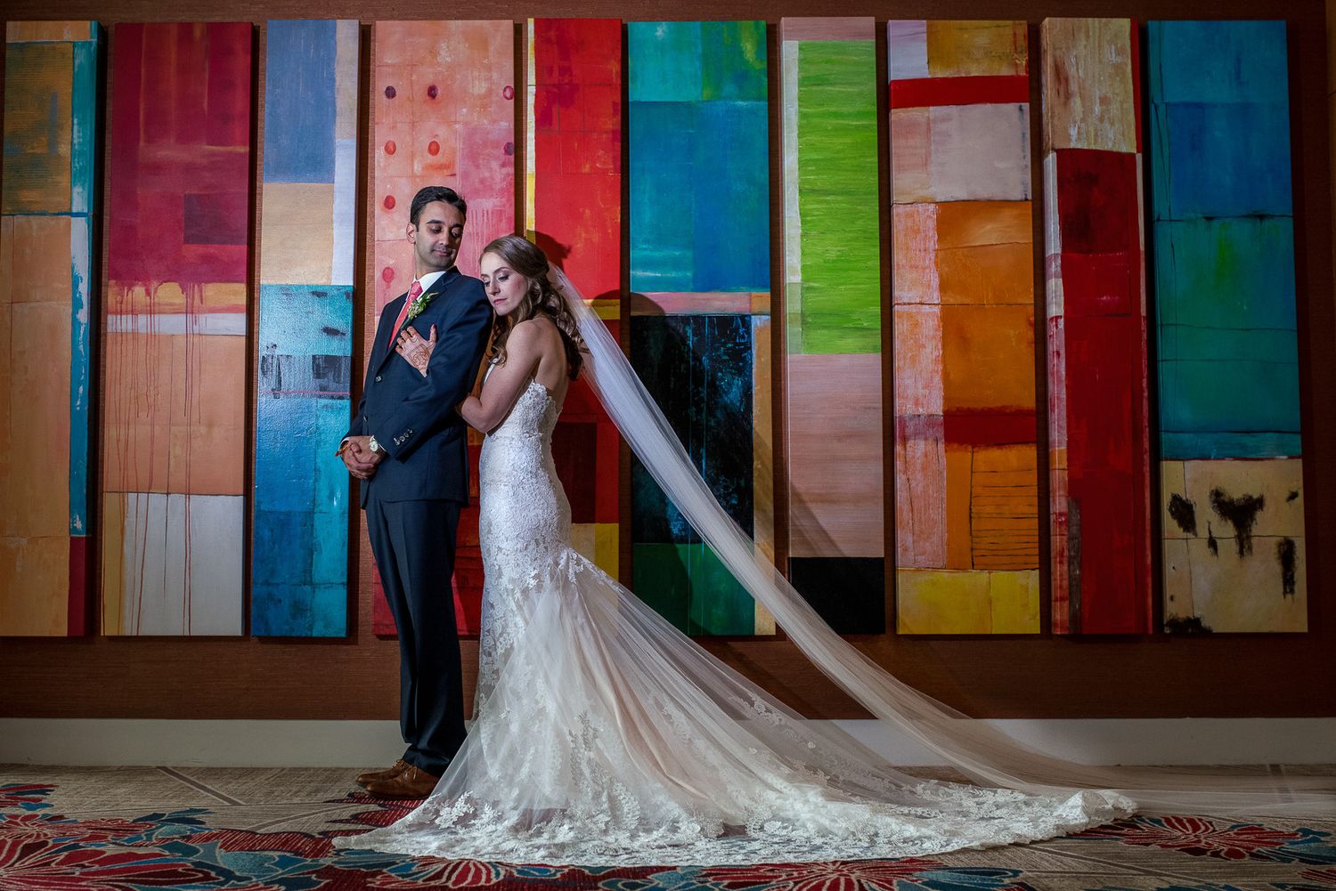 Wedding couple poses against colorful wooden wall backdrop.