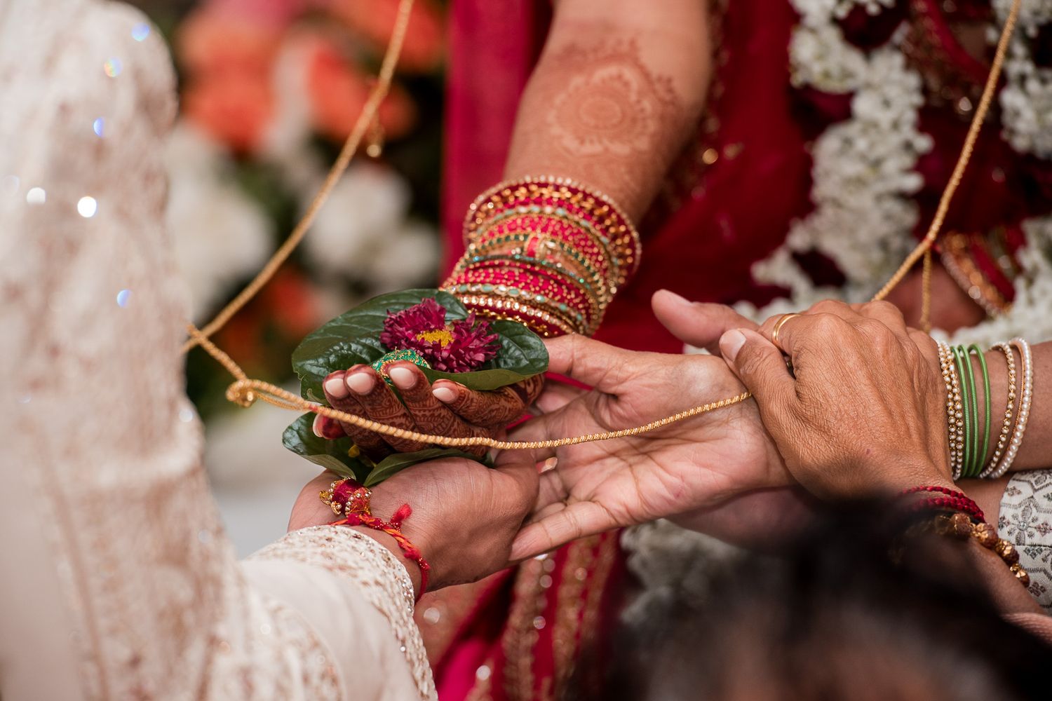Traditional Indian wedding ceremony ritual showing decorated hands exchanging offerings.