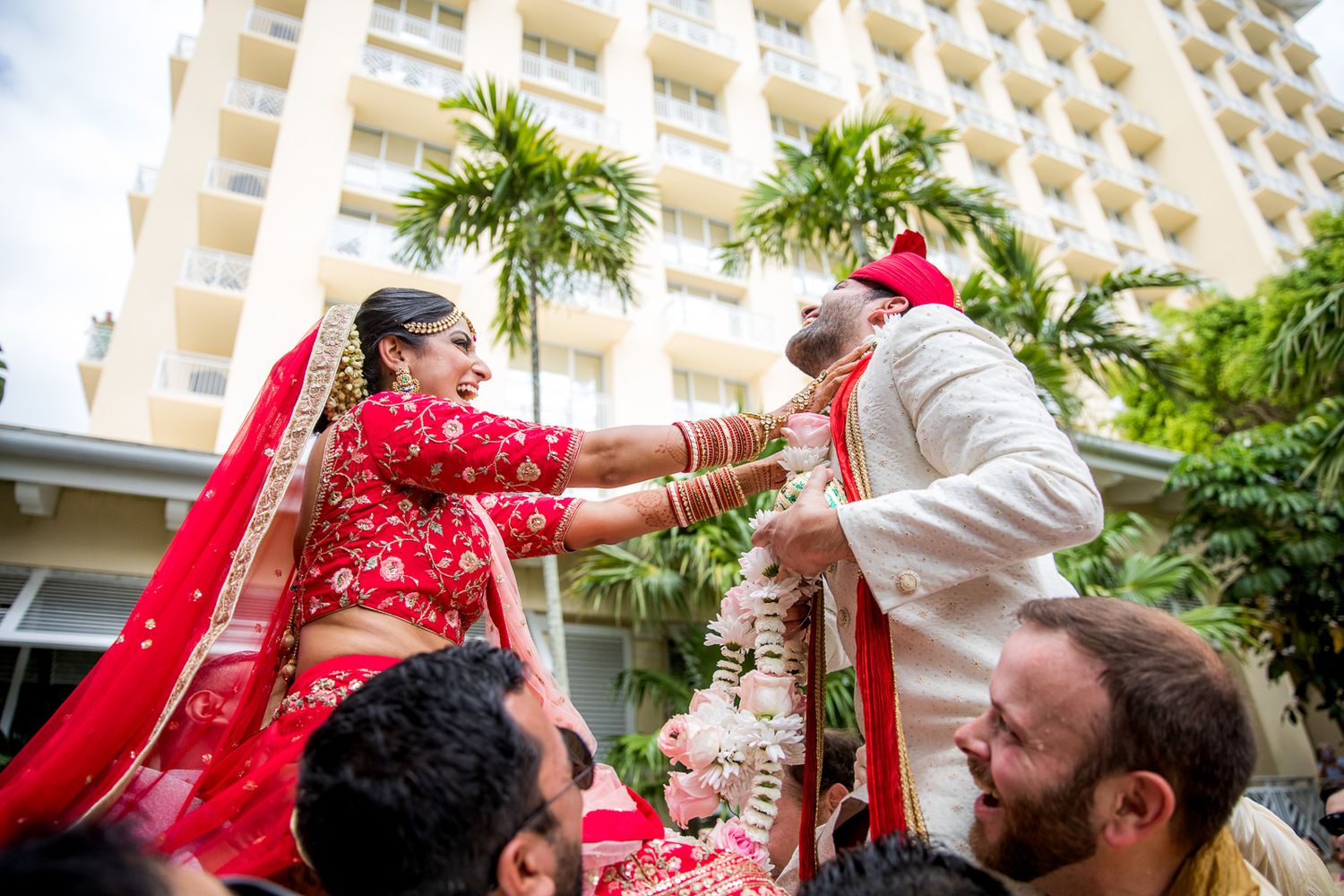 Traditional Indian wedding ceremony with couple performing ritual under hotel balconies.