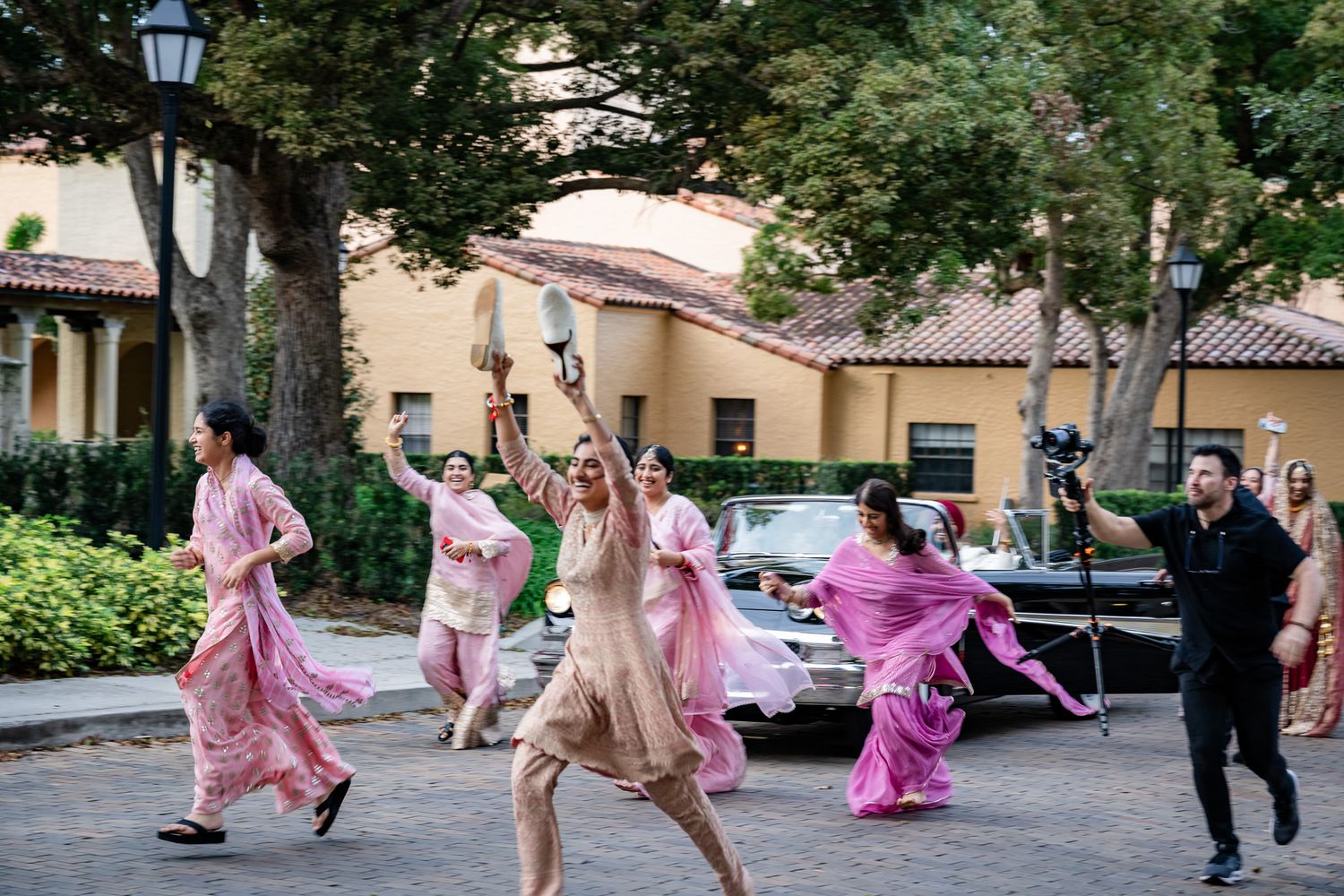 Wedding party dancing and celebrating in pink attire on outdoor street.