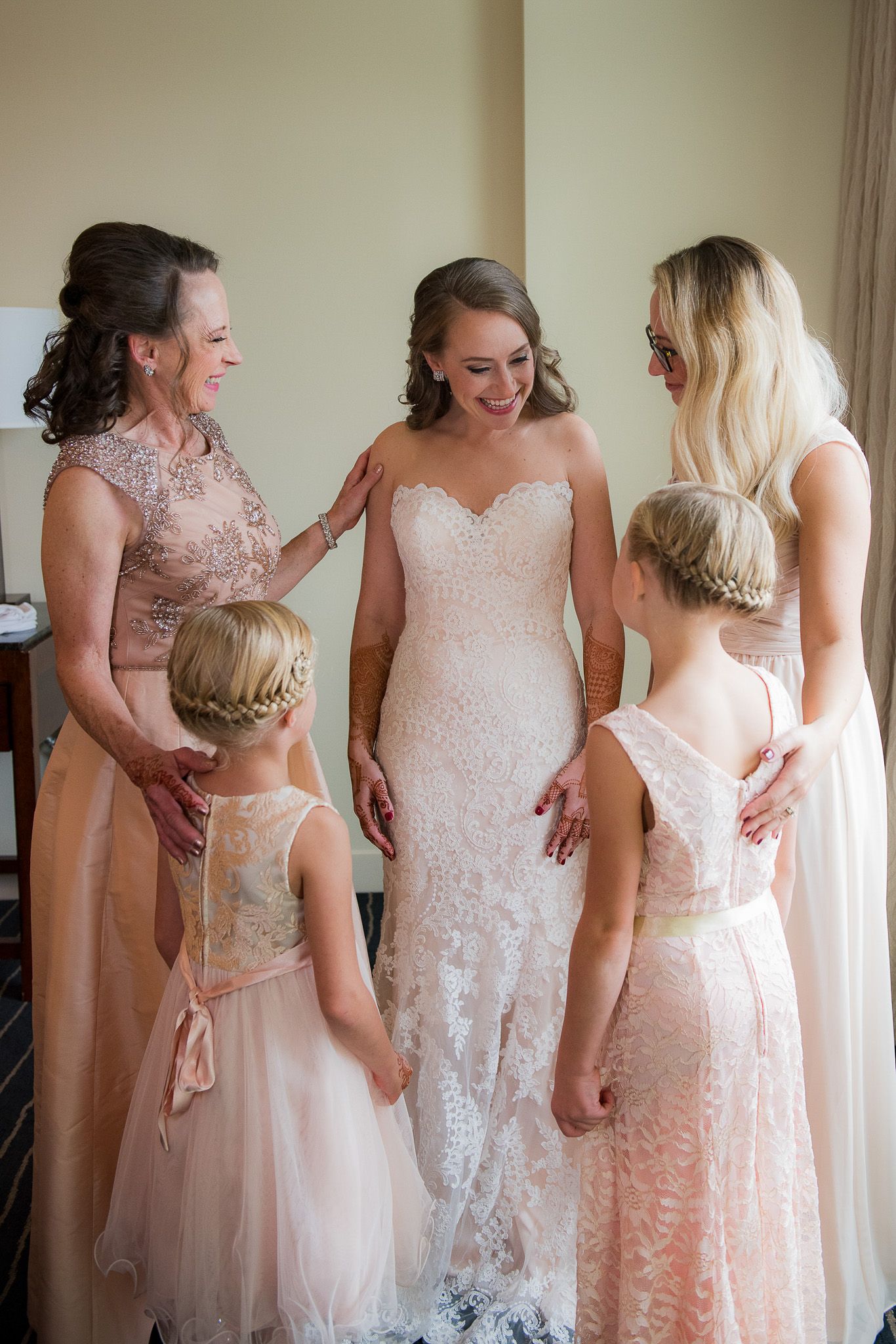 Wedding party wearing soft pink and white dresses pose together.