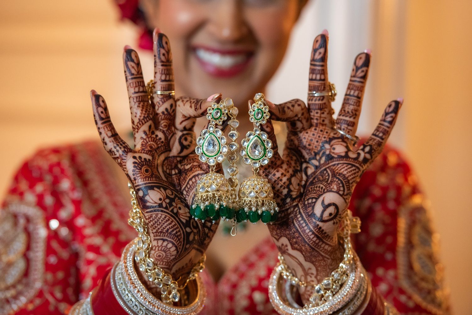 Detailed mehndi henna designs on hands with ornate jewelry and bangles.