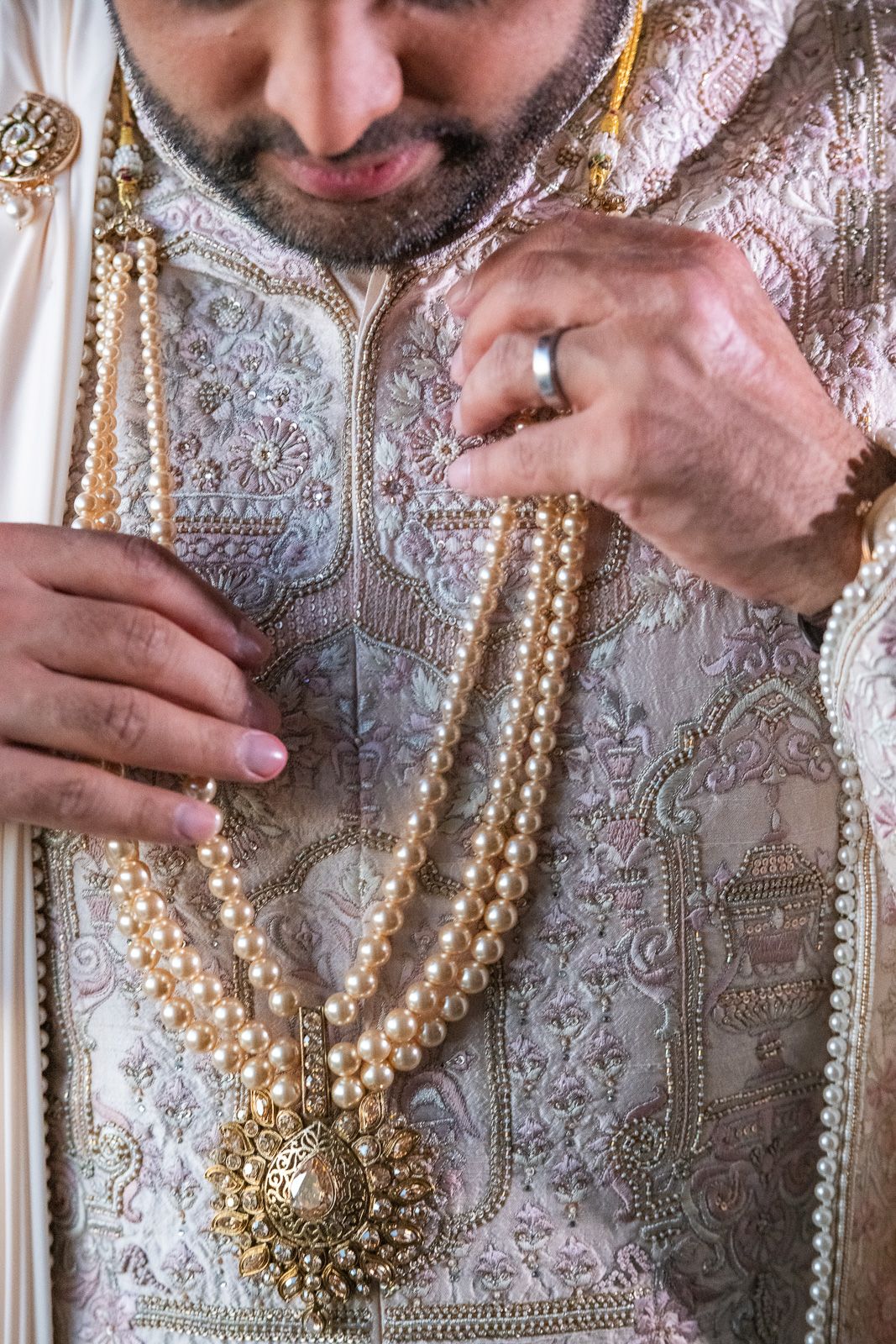 Detailed shot of ornate pearl necklace and embroidered traditional Indian wedding attire.