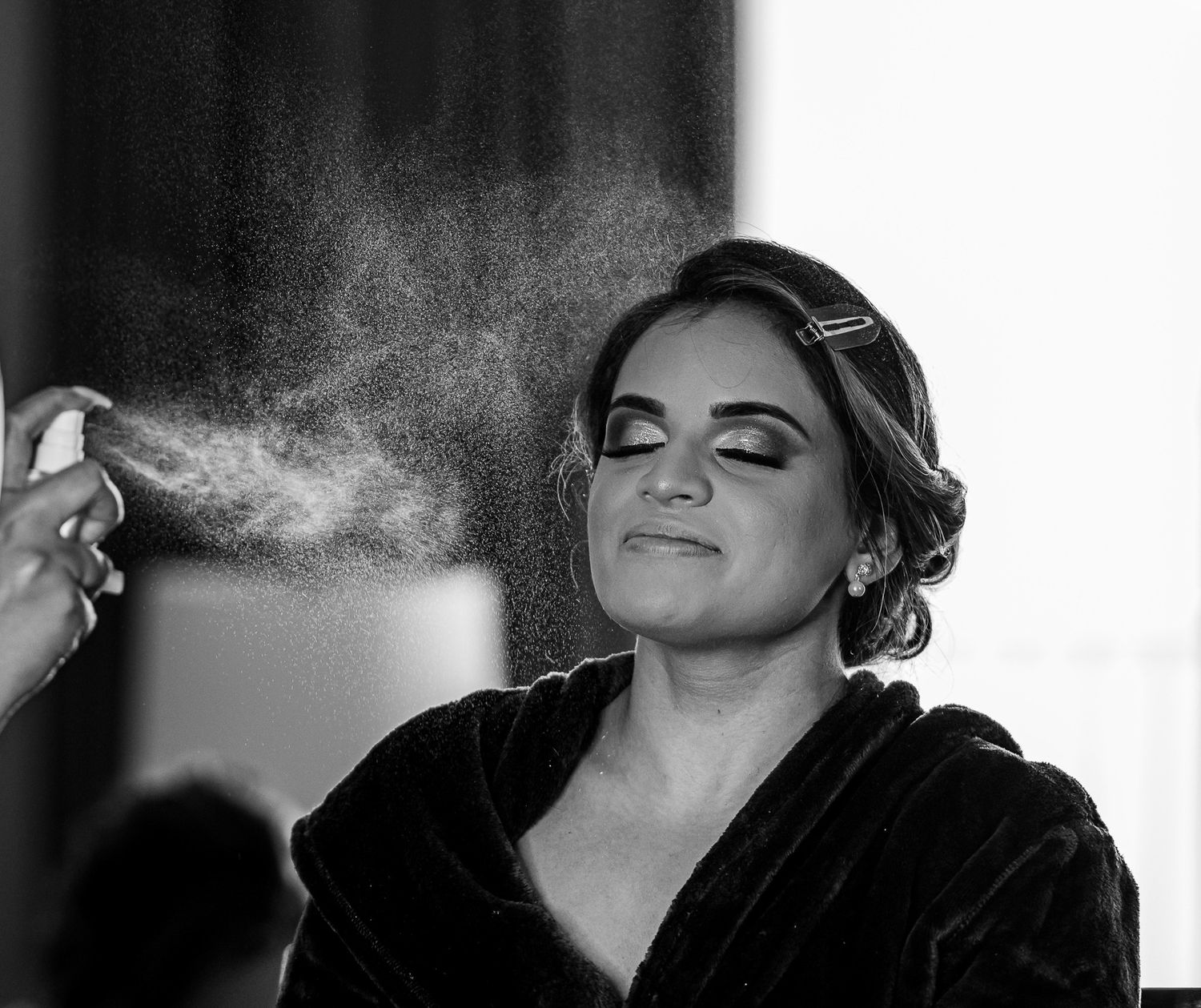 Black and white image of hairspray being applied during wedding preparations.