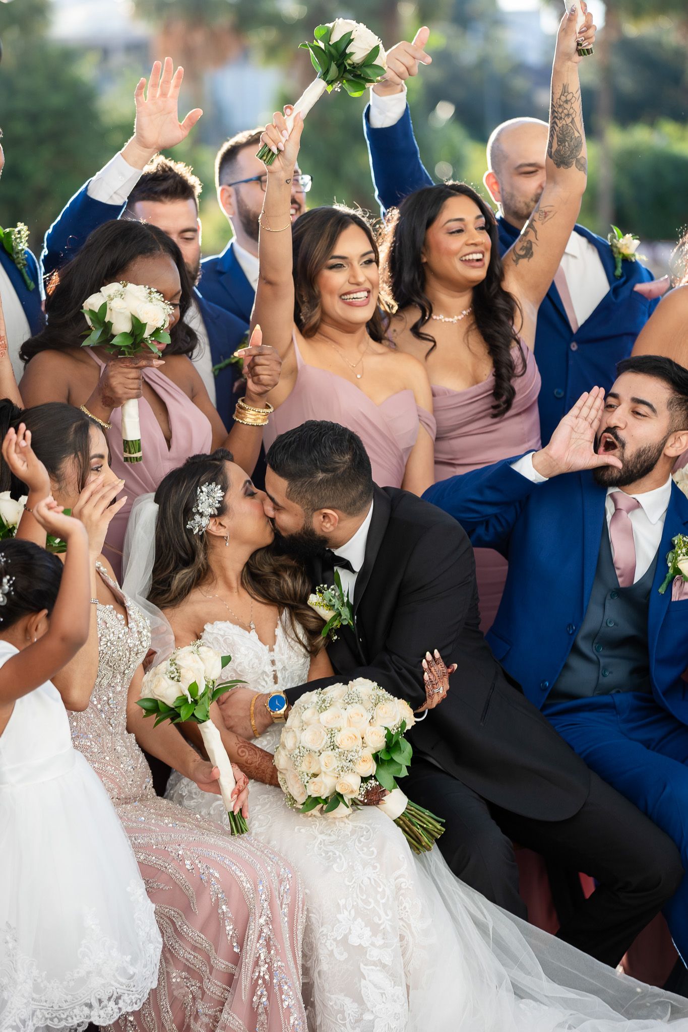 A joyous wedding celebration with the bridal party in blue suits and pink dresses.