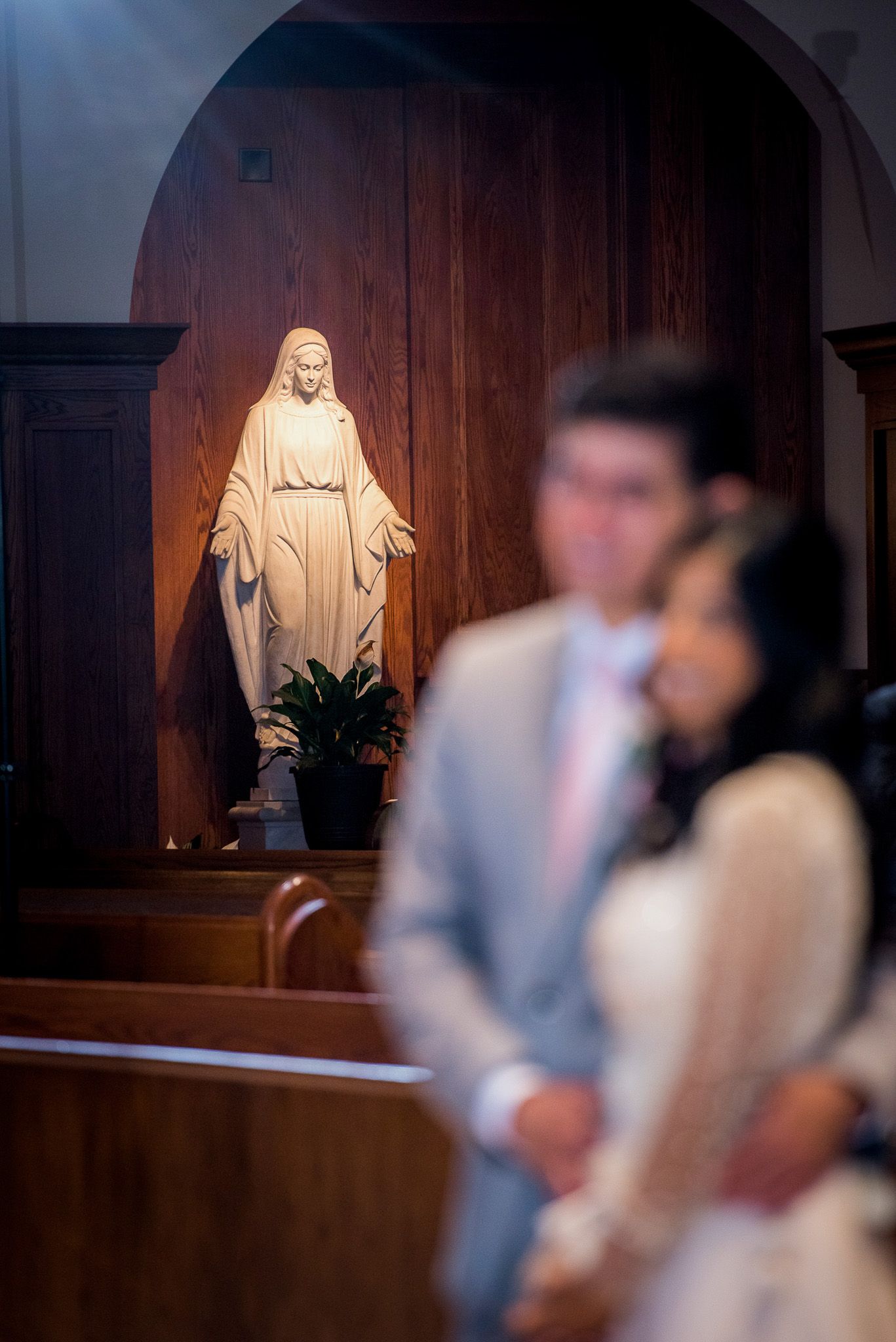 A religious statue illuminated in the background of a church setting.