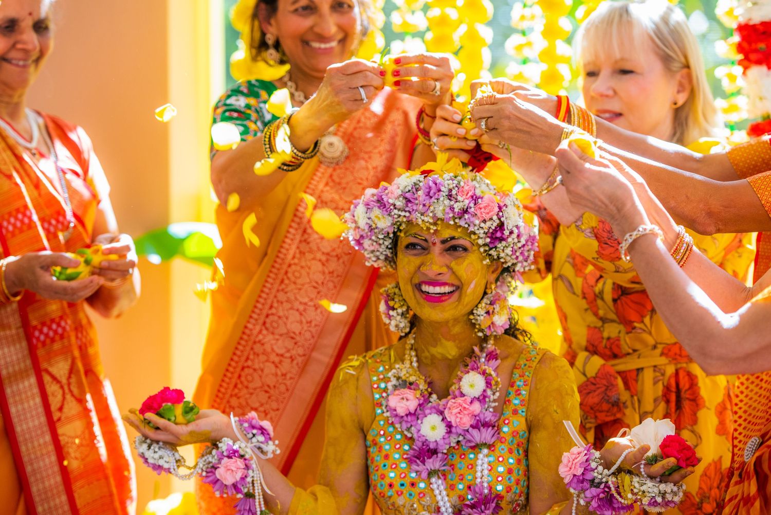Joyful haldi ceremony with guests applying turmeric paste during pre-wedding celebration.