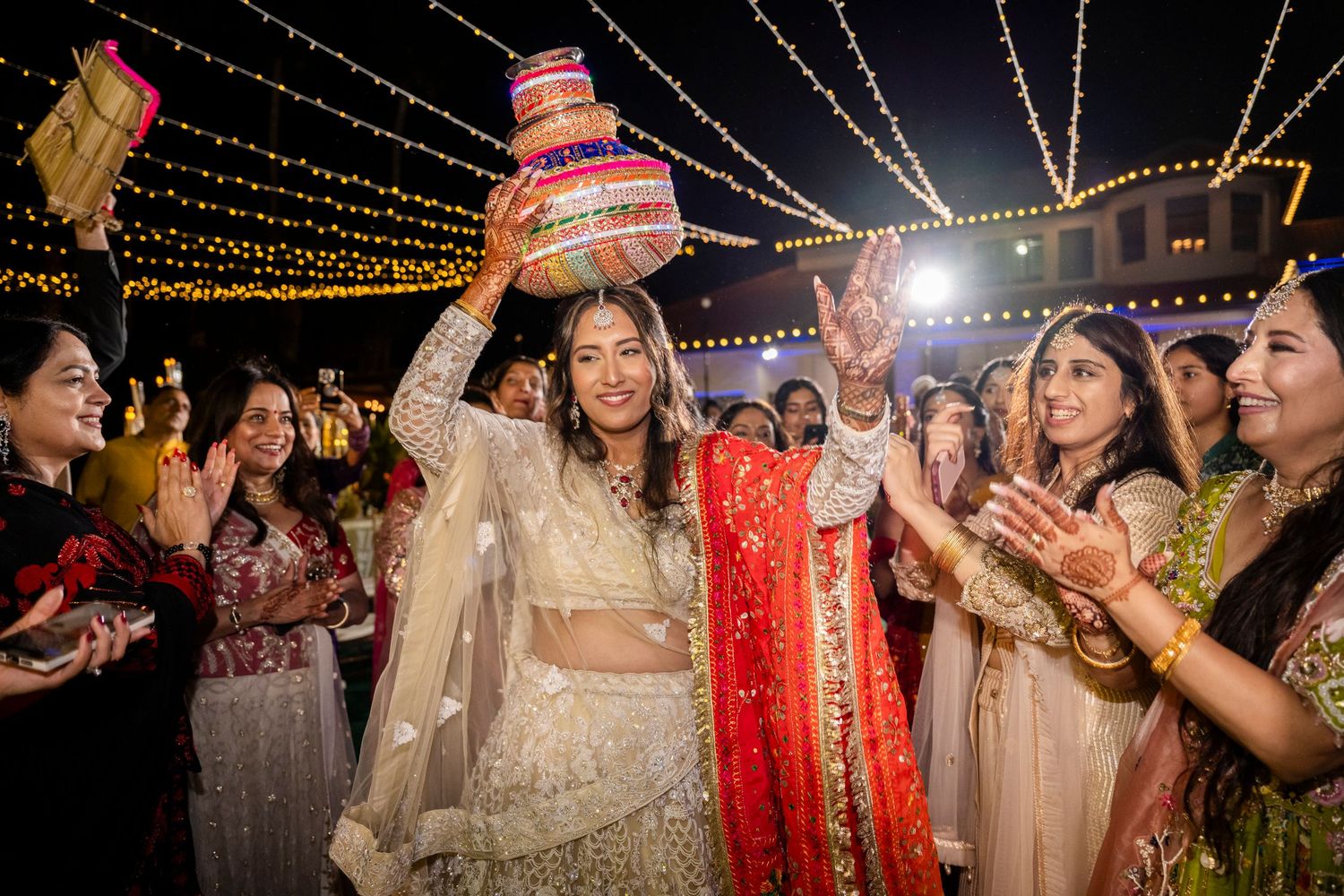 Festive night celebration with string lights where guests participate in traditional wedding customs.