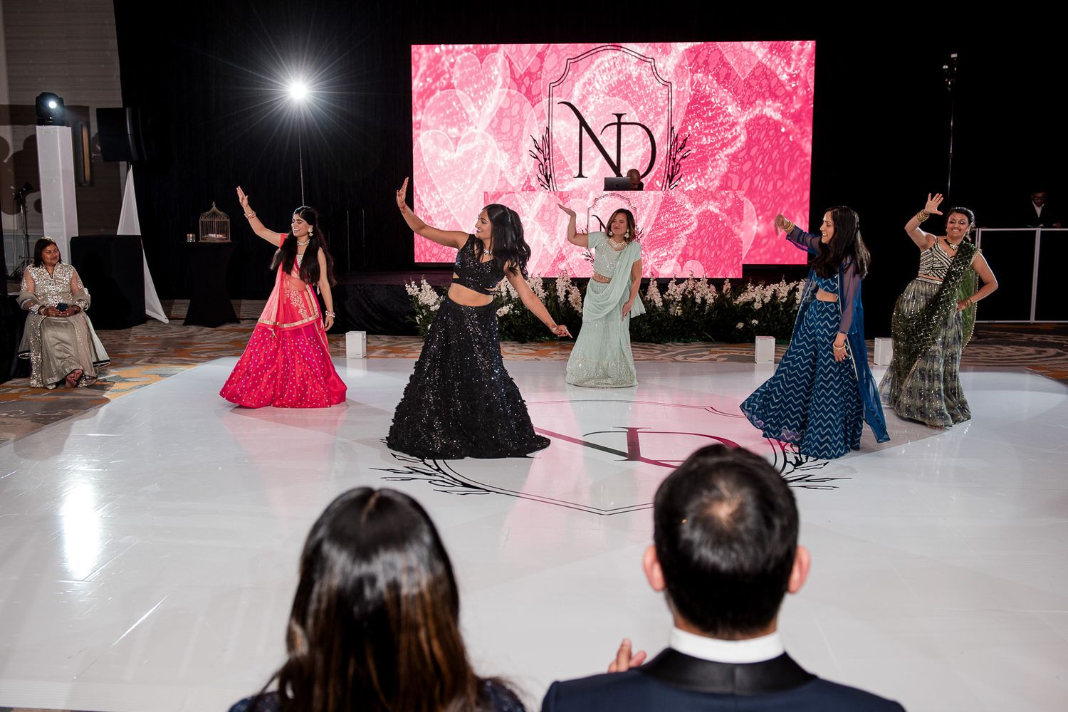 Dancers performing choreographed routine on white stage with pink backdrop displaying ND logo.