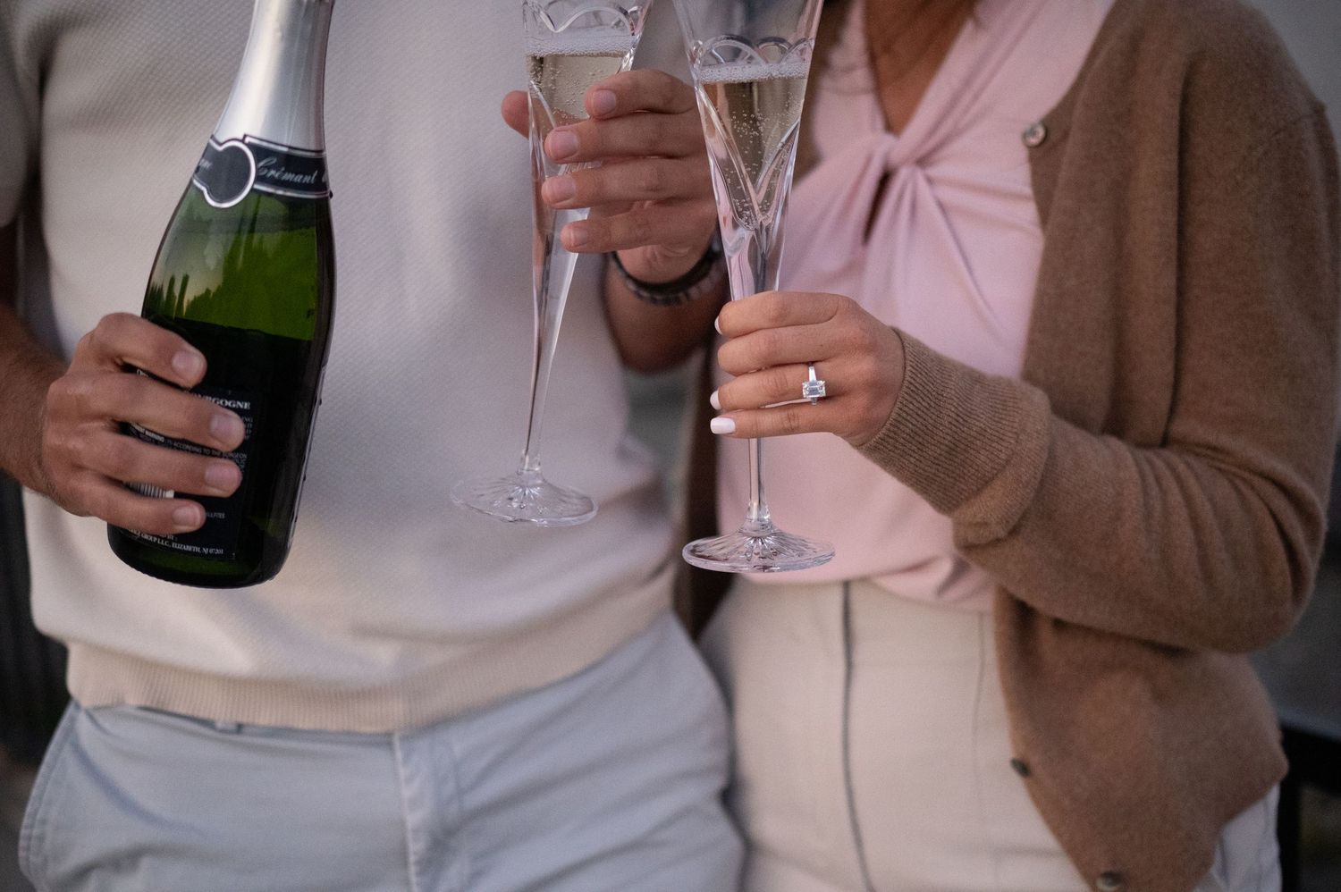 People holding and toasting with champagne glasses and bottles during a celebration event.
