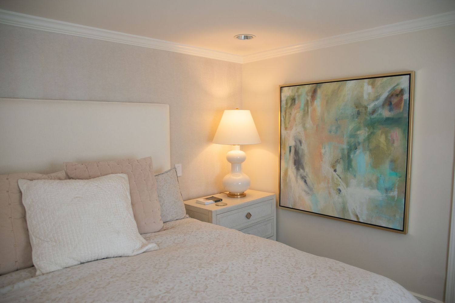 Cozy bedroom with coastal artwork, white bedding, and built-in storage features.