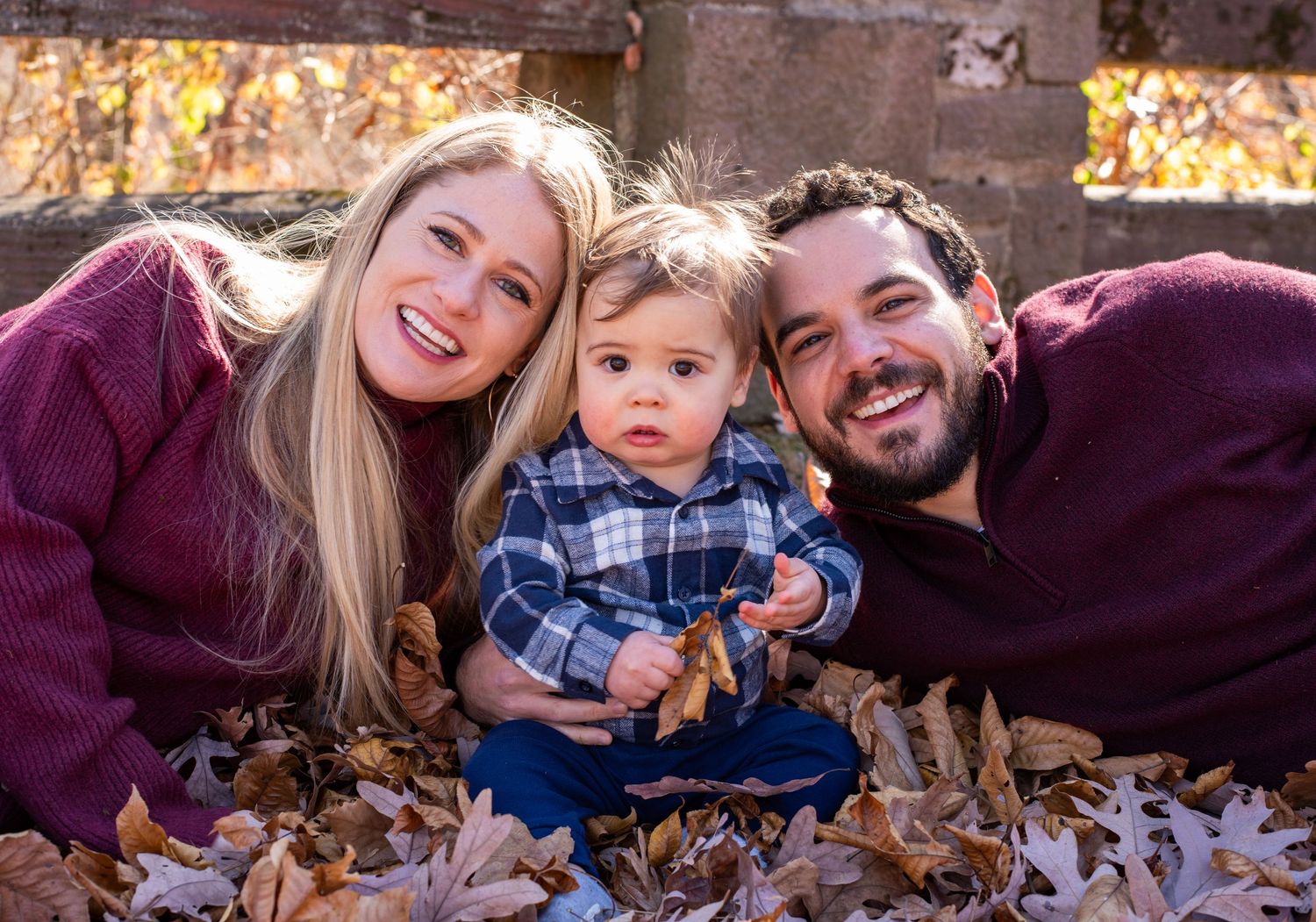 People lying in autumn leaves during a fall photo session.