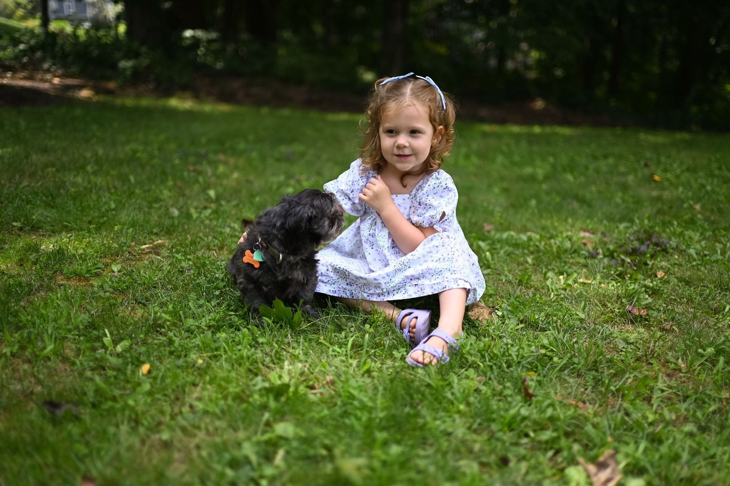 Child playing and rolling on green grass outdoors.