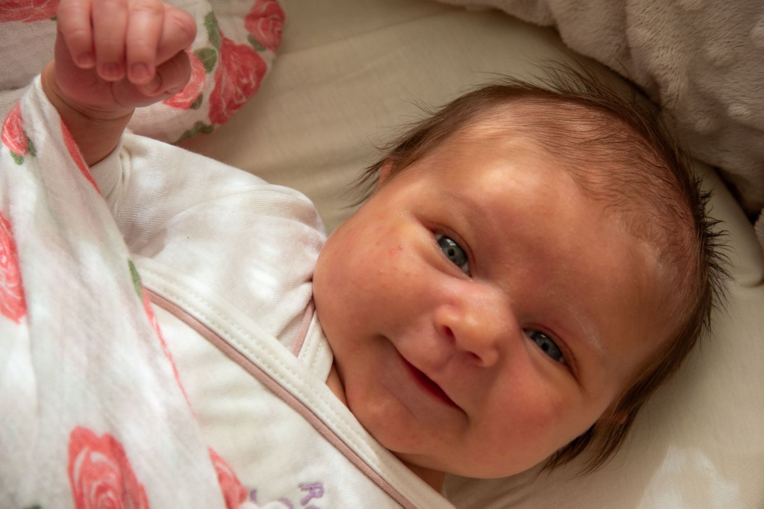Closeup portrait captures sweet innocence of newborn resting on white bedding.