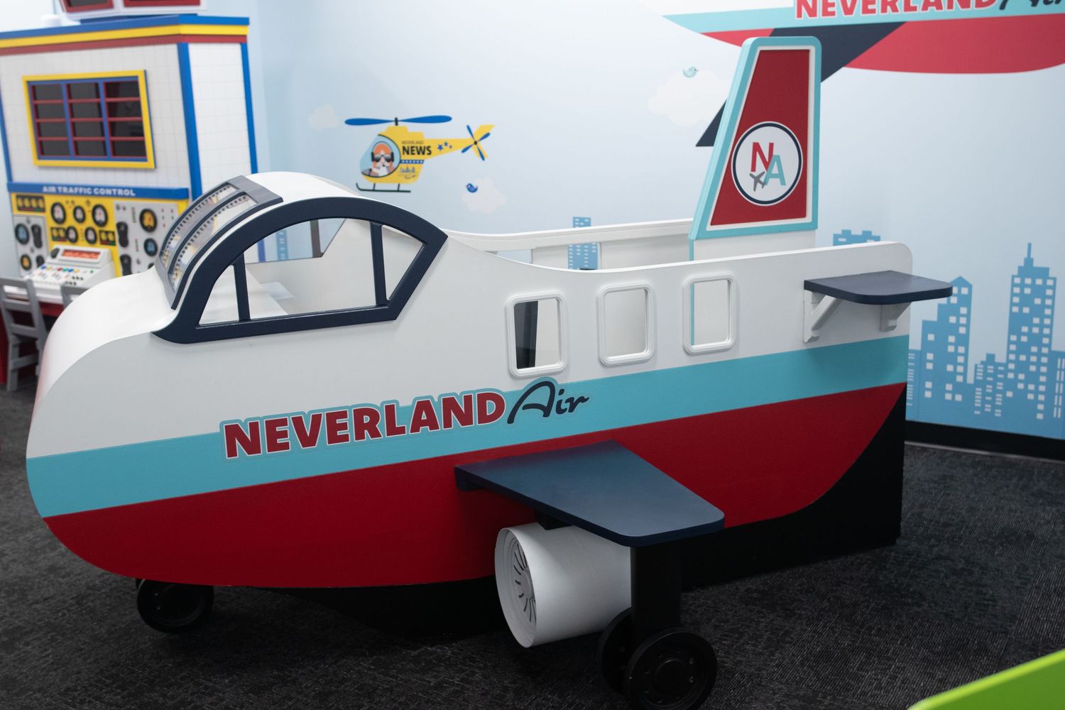 Miniature red and white model train or boat display with Neverland branding on white background.