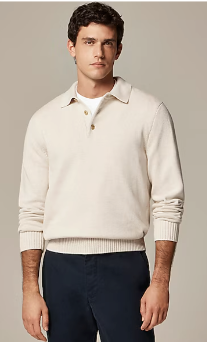 Model wearing a cream colored knit polo sweater with navy blue pants in a fashion photoshoot.