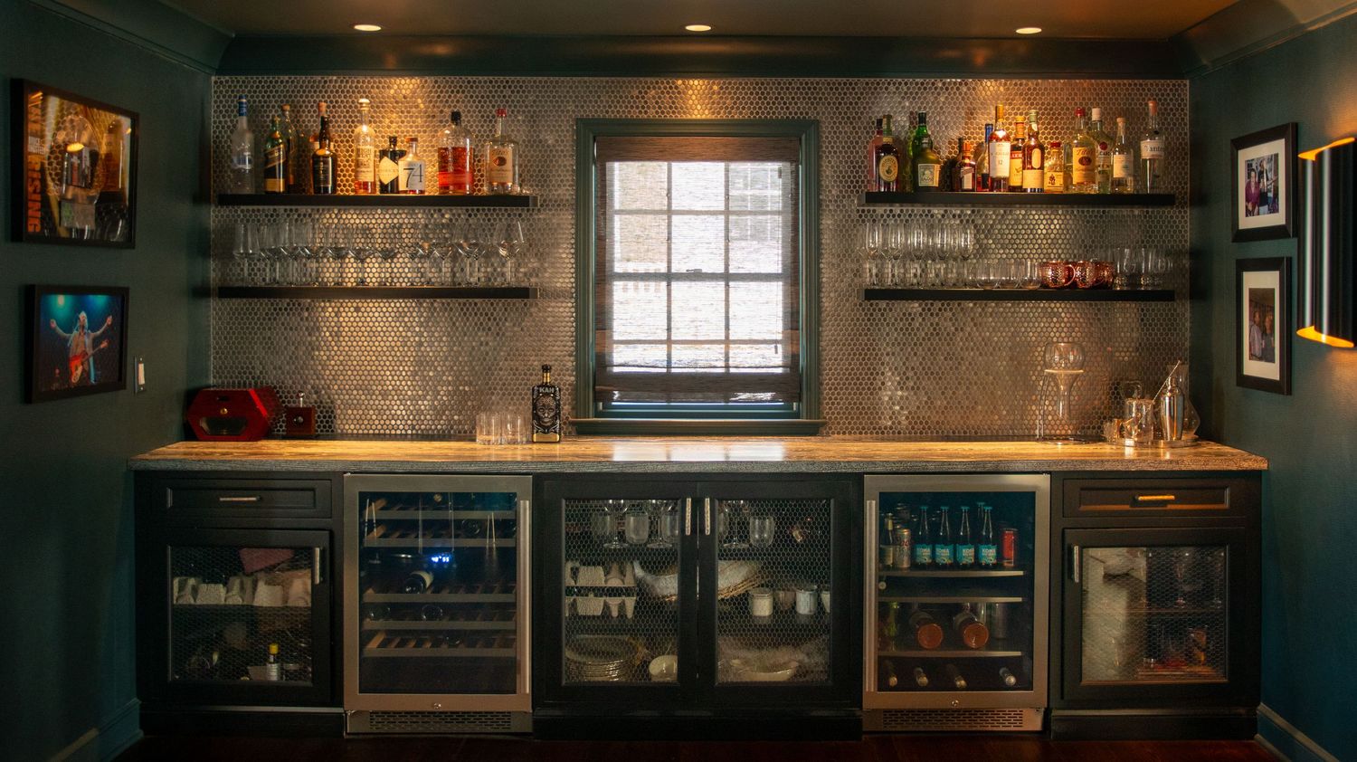 Dark moody bar interior with illuminated shelving displaying bottles and glassware.