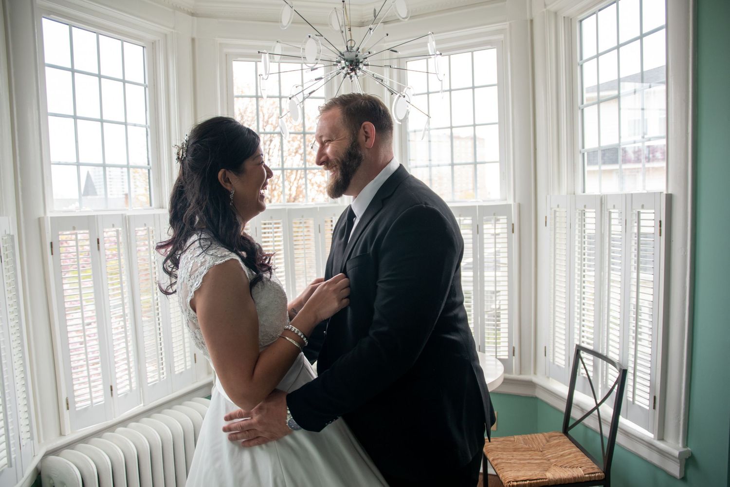 Couple sharing tender moments in bright sunlit room with large windows.