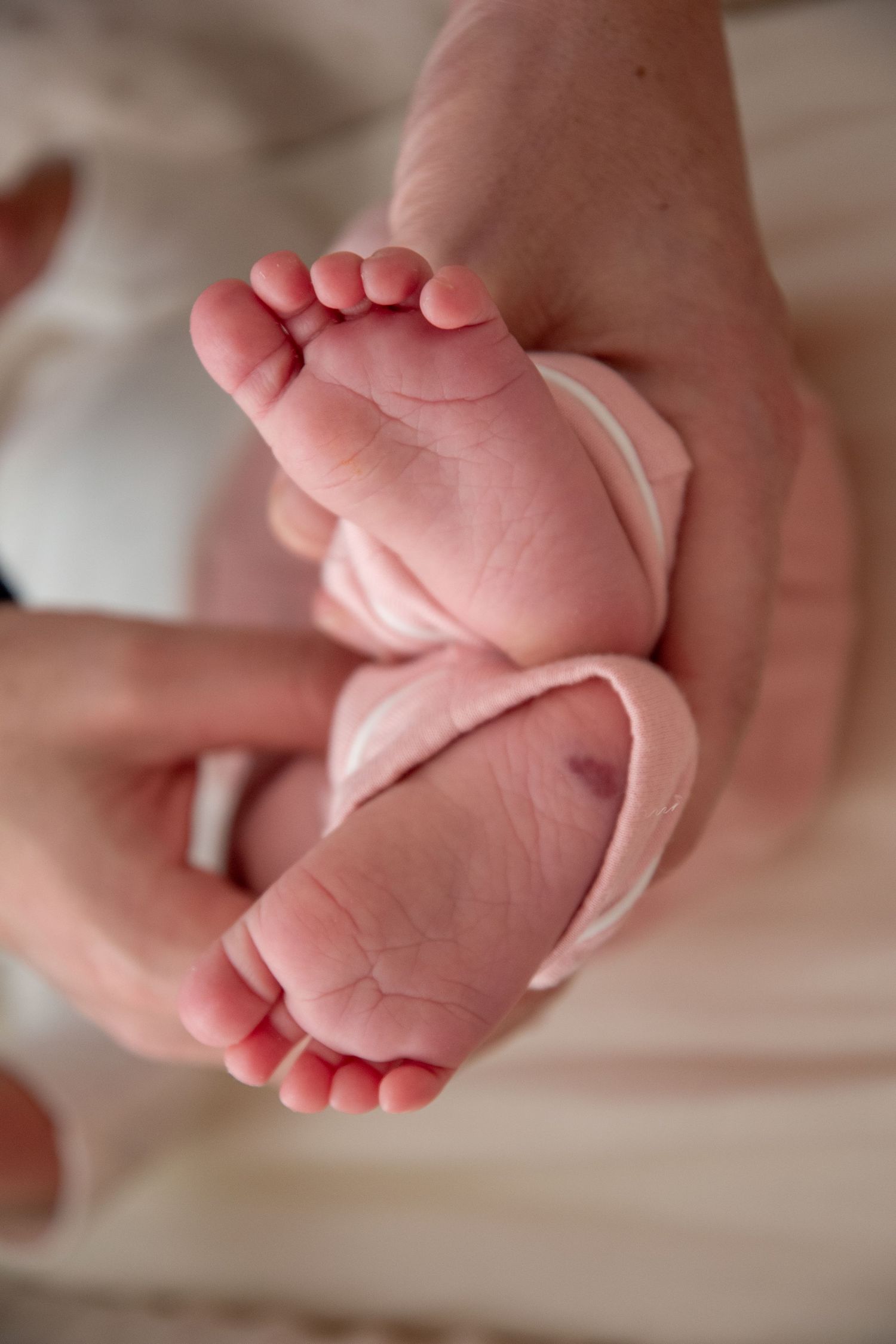 Tiny newborn baby feet and toes close up showing delicate pink skin.