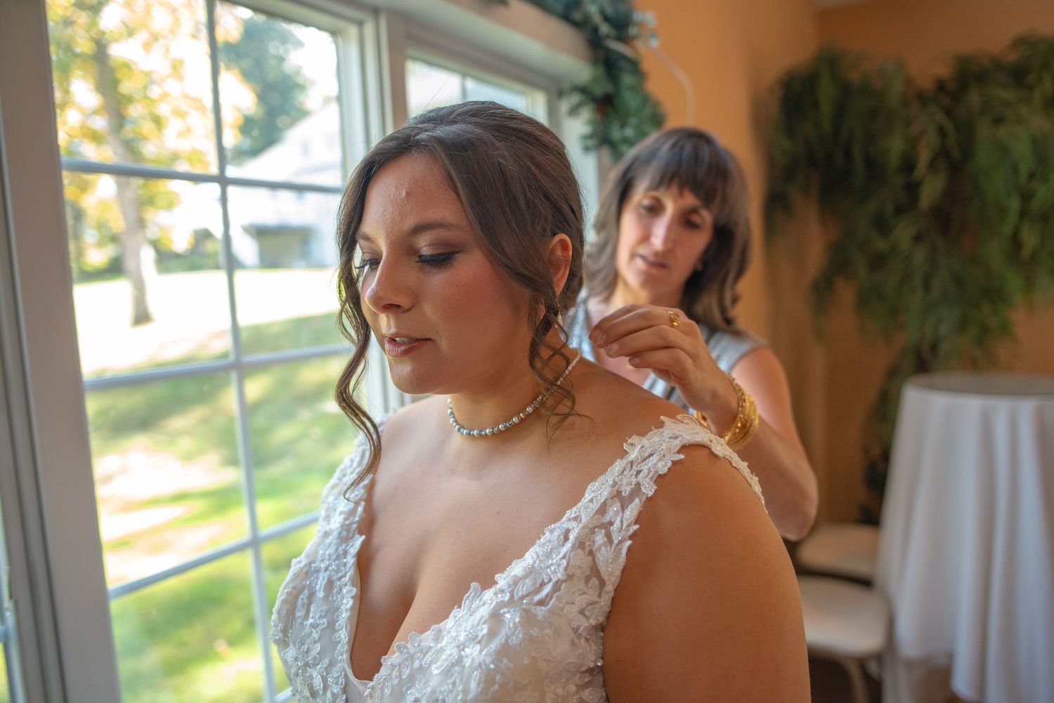 A bride in a white lace dress gets final adjustments before her wedding ceremony.