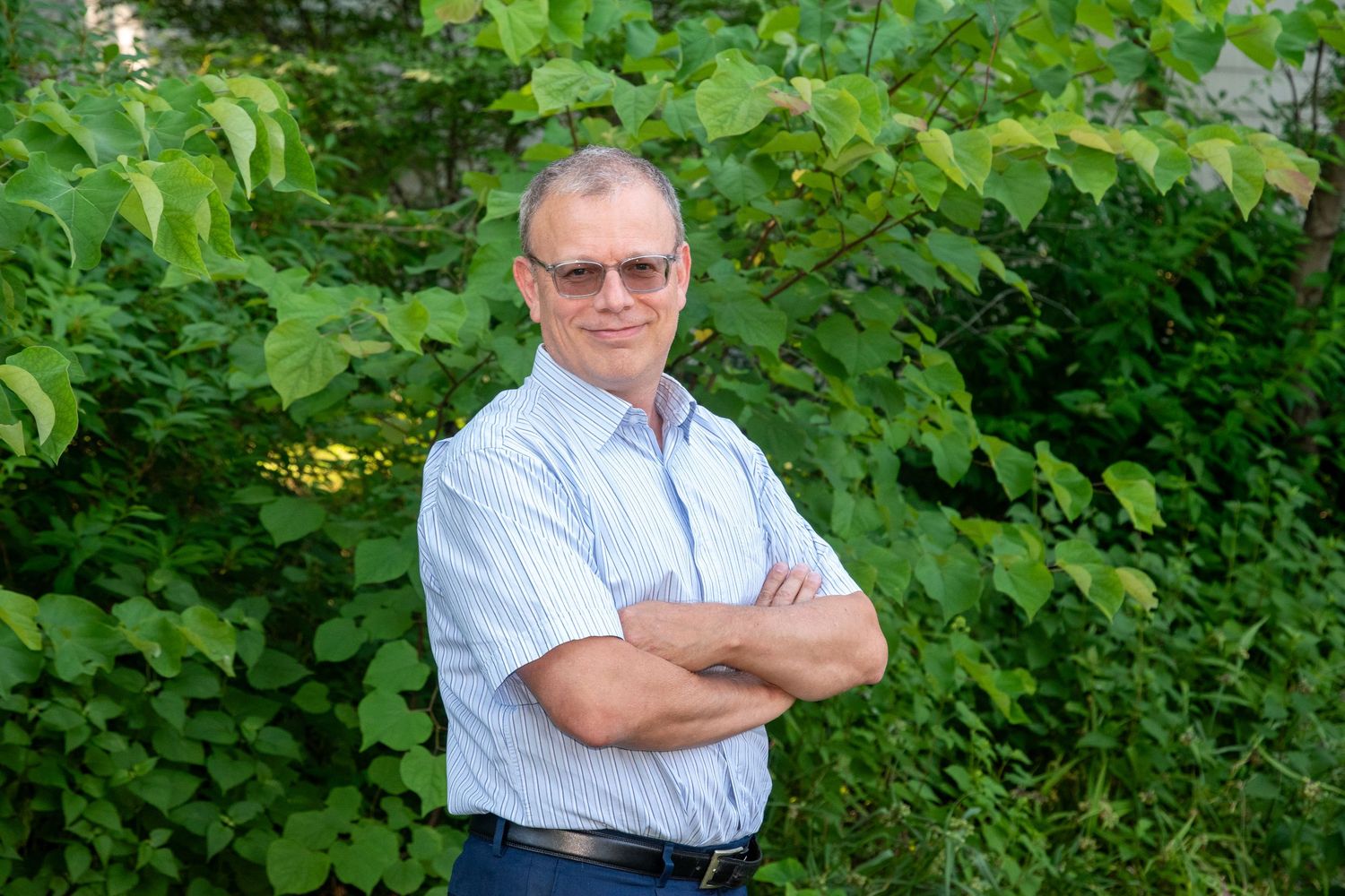Professional outdoor portraits against green foliage wearing business attire.