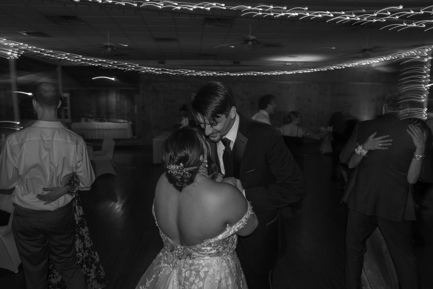 Dance floor celebration with string lights overhead at evening reception.