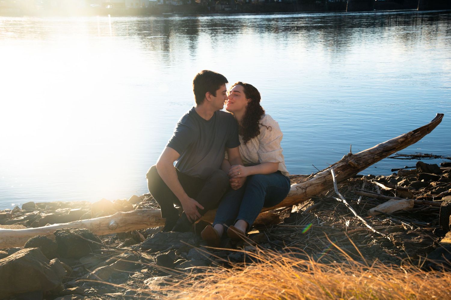 Silhouetted couple shares intimate moment by lakeside during sunset.
