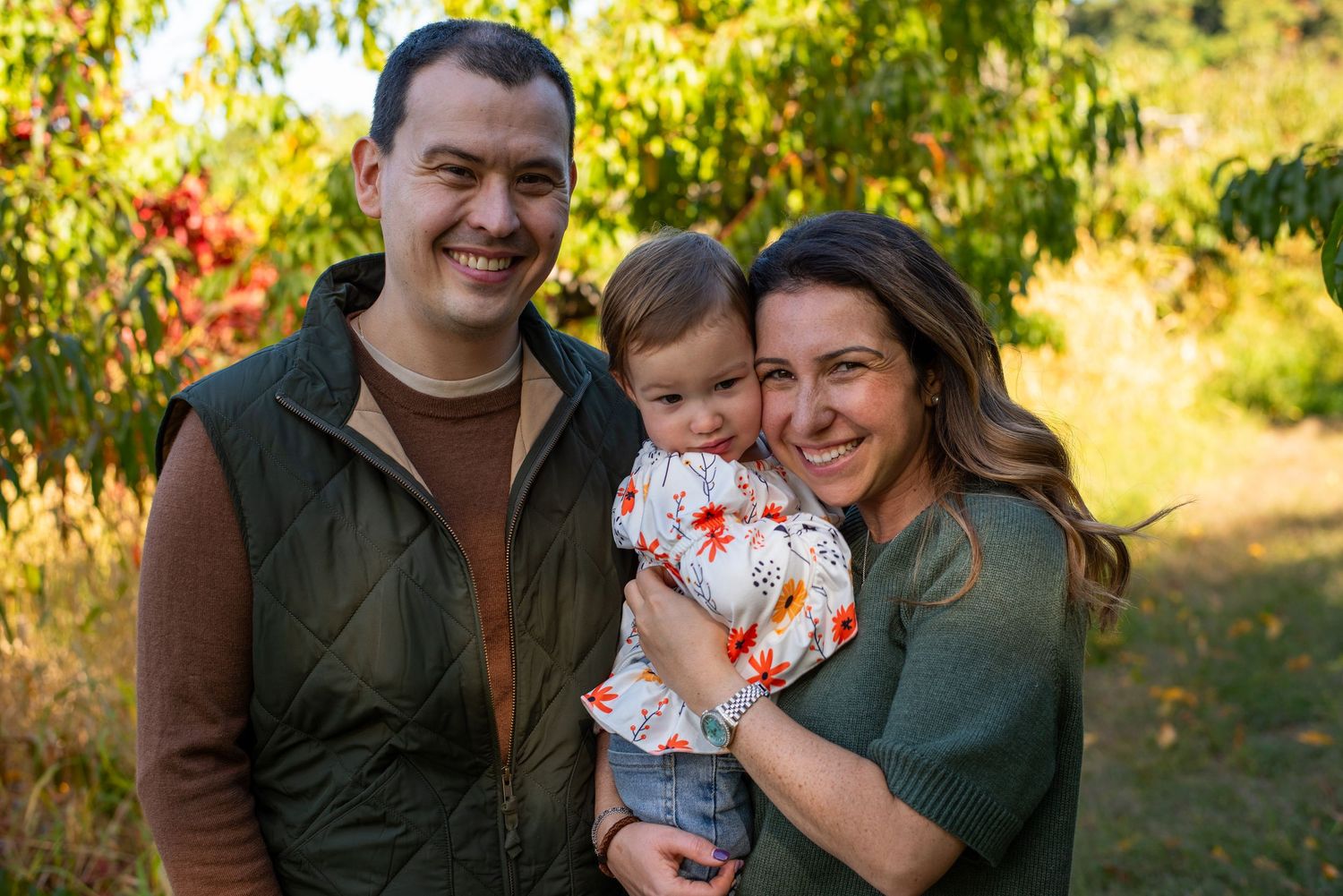 An outdoor family photo shoot in a golden field during sunset.