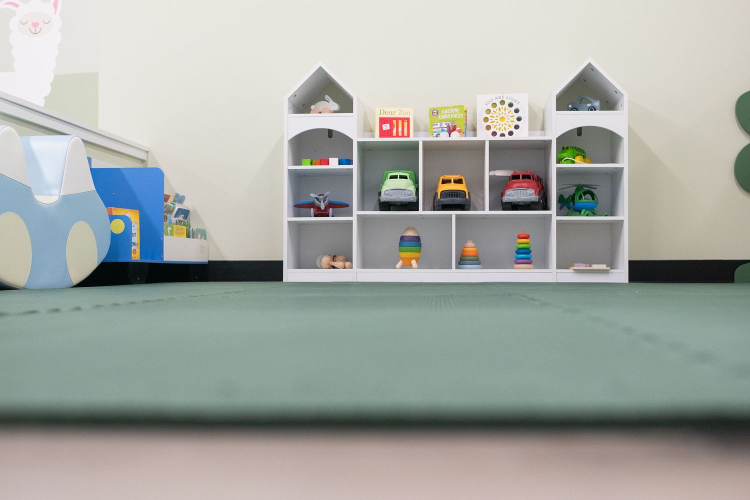Children's play area shelving unit with colorful toys and small houses displayed.