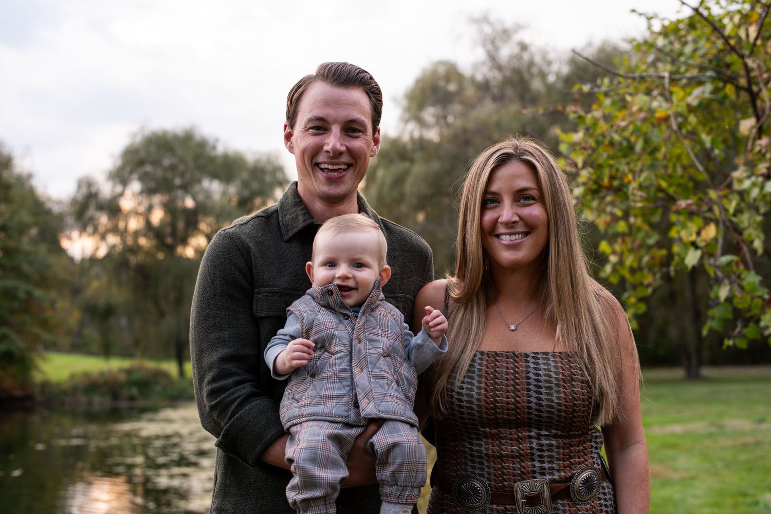 Family enjoying a warm autumn day outdoors in a park setting with trees and natural lighting.