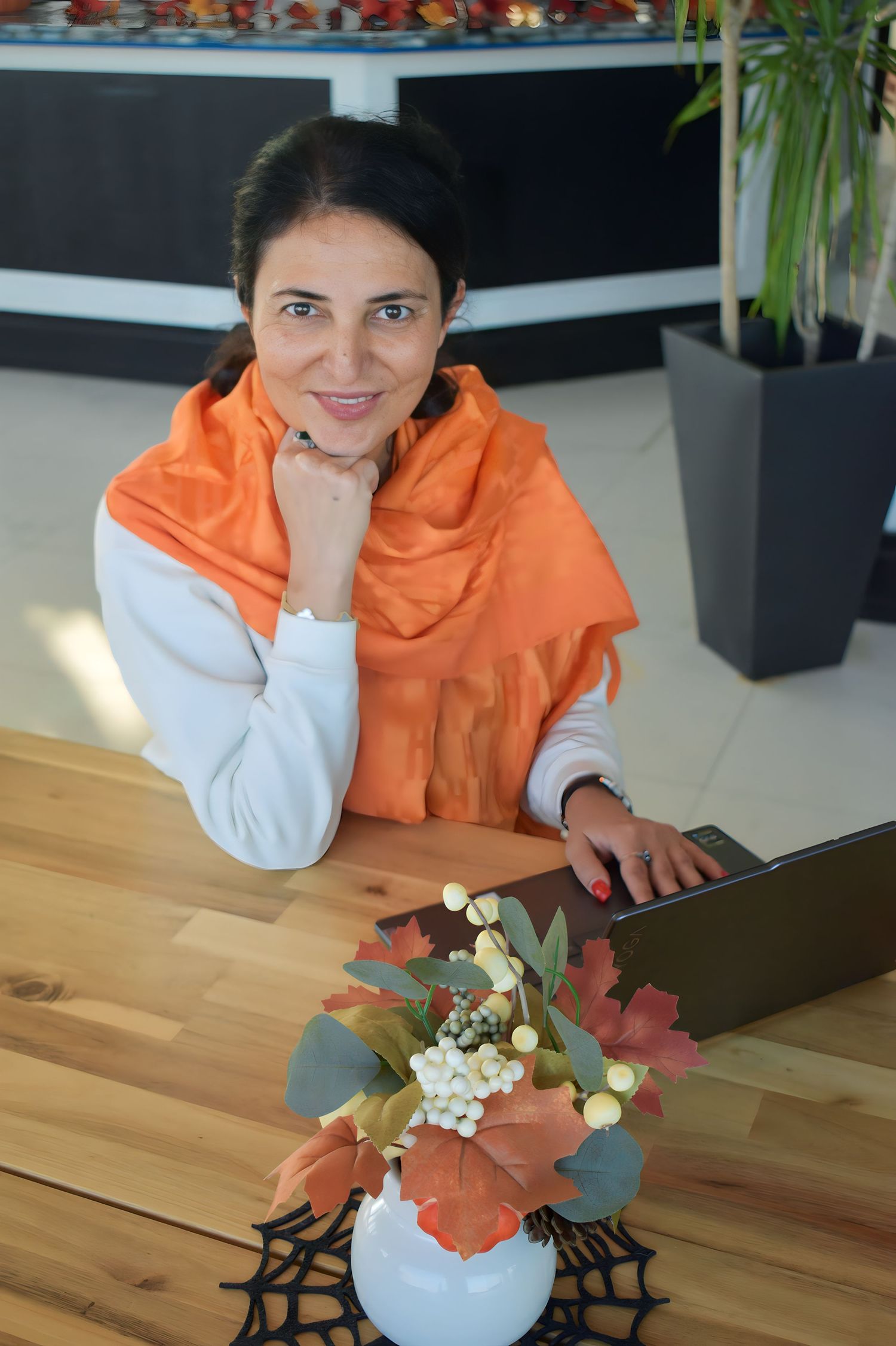 Indoor workspace scene with orange decor and floral arrangement on wooden desk.