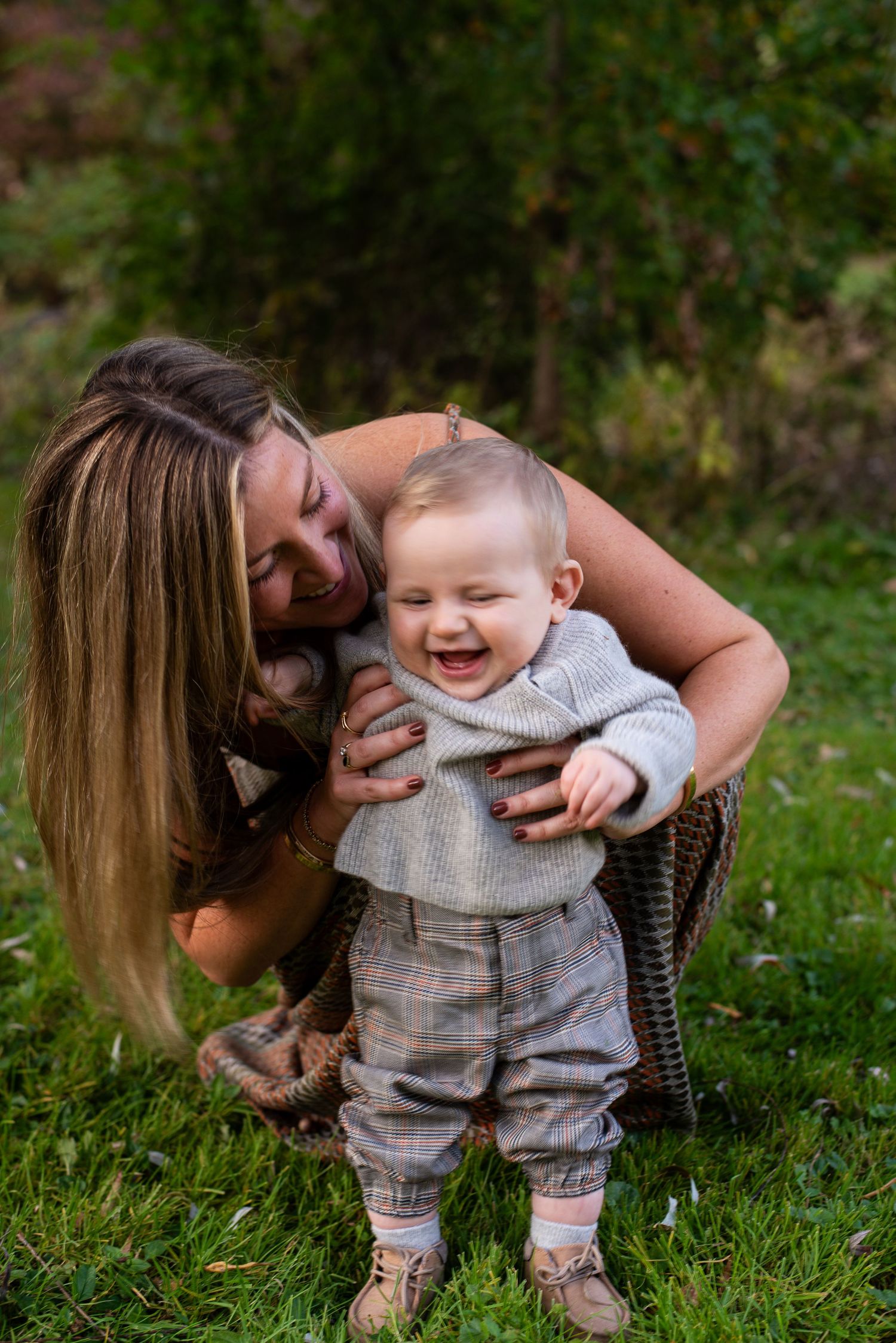A sequence of joyful moments captured between a parent and baby playing on green grass outdoors.