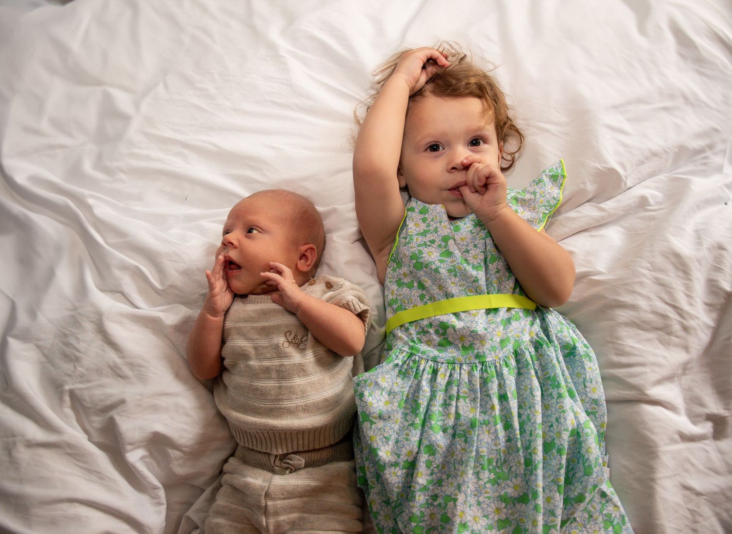 Sequential photos showing a baby in a floral dress laying on white bedding.