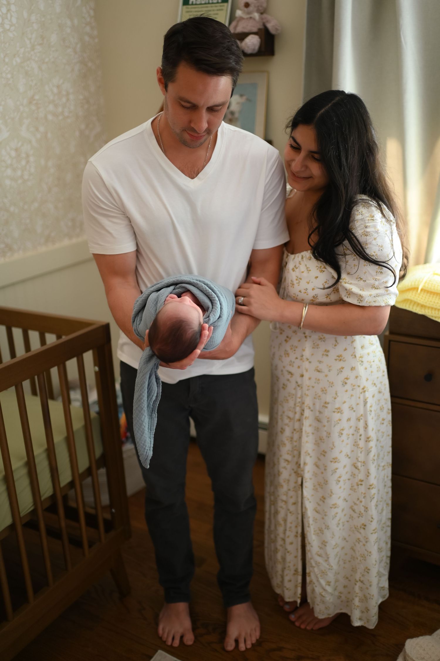 New parents sharing tender moments with newborn baby in nursery setting.