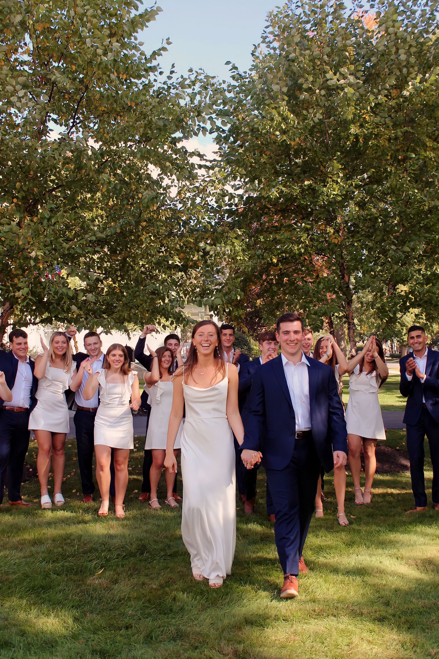 Wedding guests dancing together in an orchard on a sunny summer day.