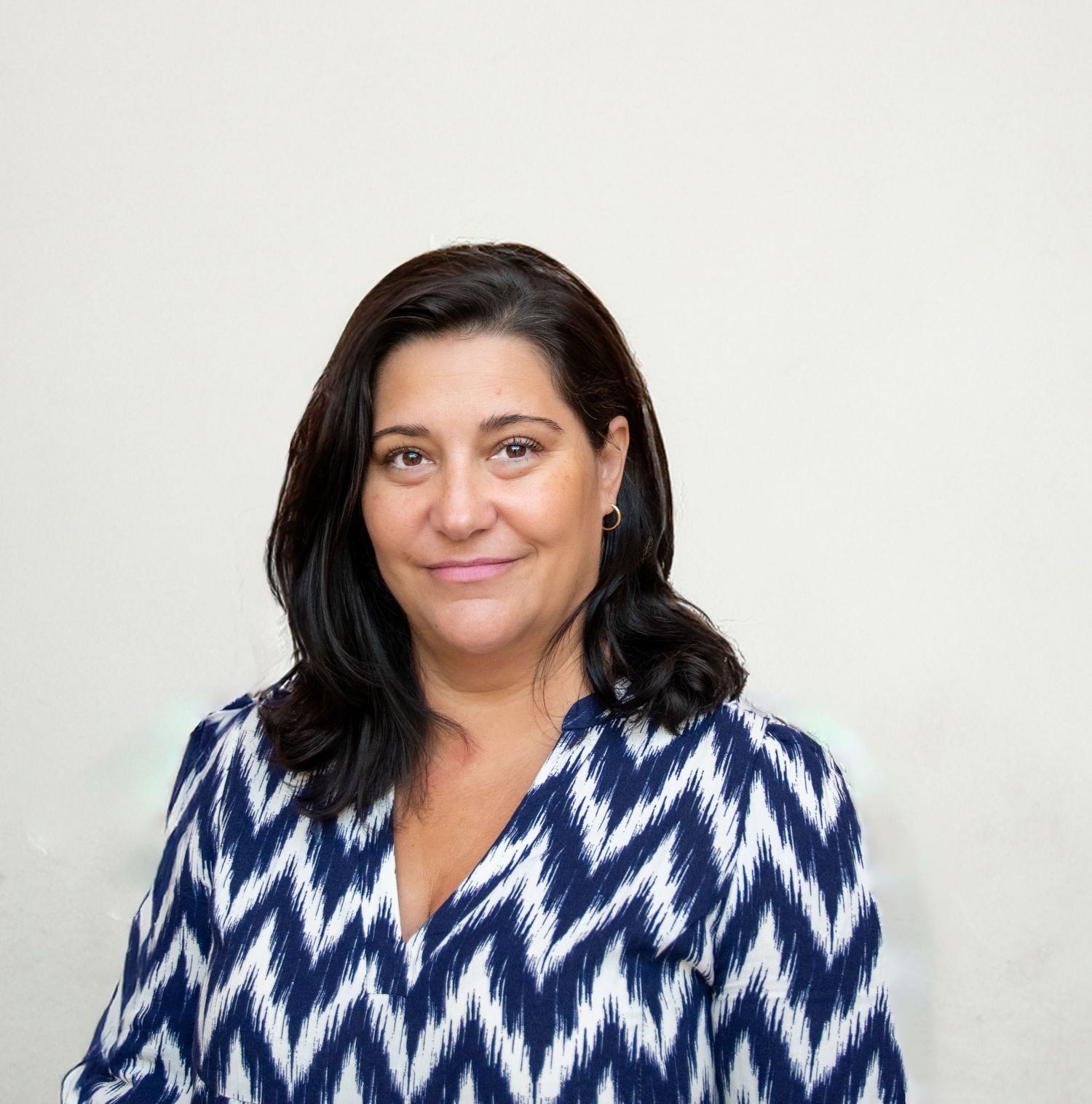 A person wearing a blue and white chevron patterned top smiling in a casual portrait series.