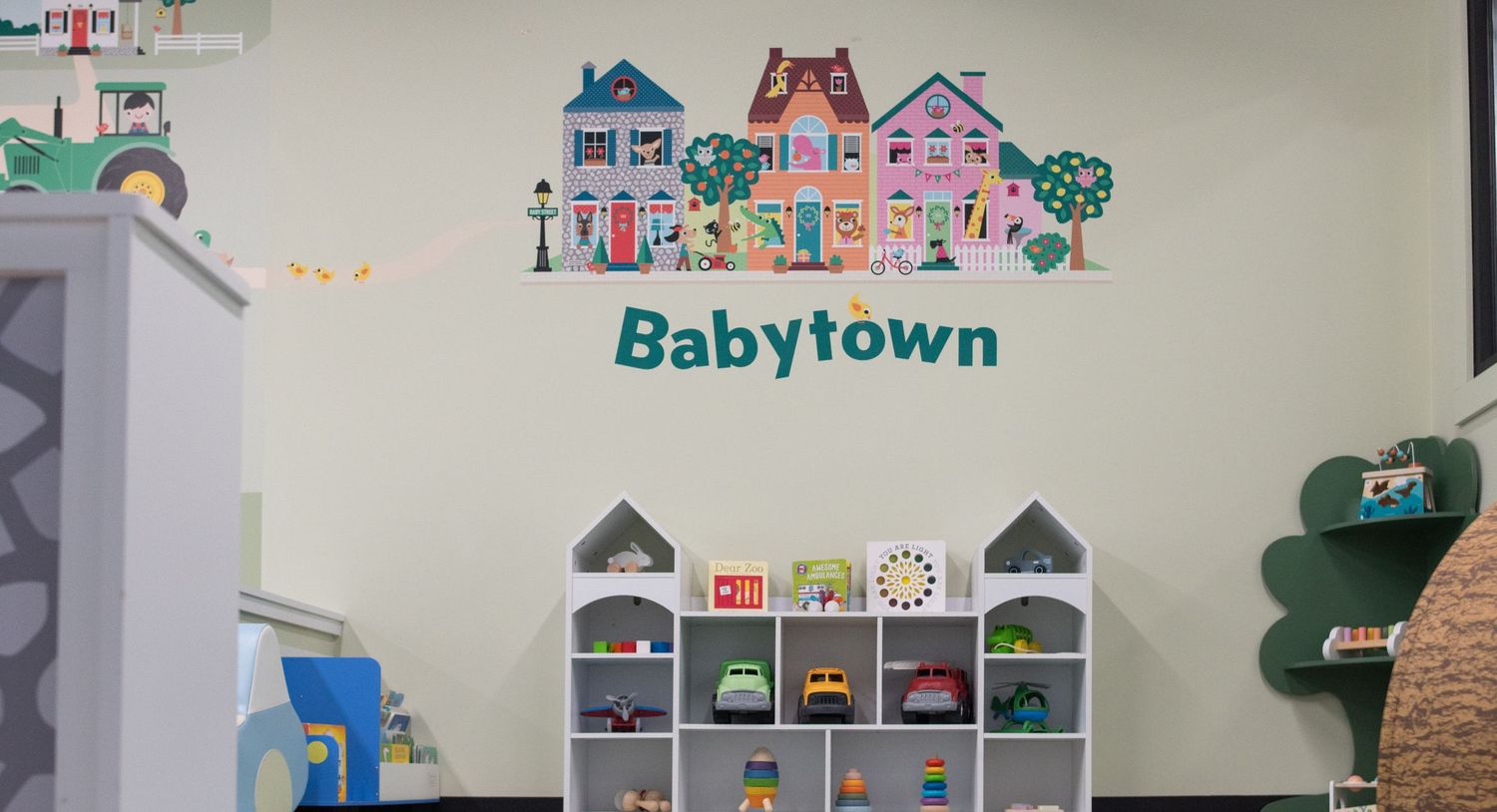 Miniature toy town display with colorful houses and rainbow decorations on wall.