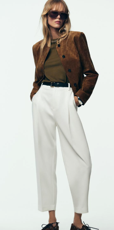 Fashion model wearing brown suede jacket, olive top, white culottes and dark sunglasses in three poses against white background.