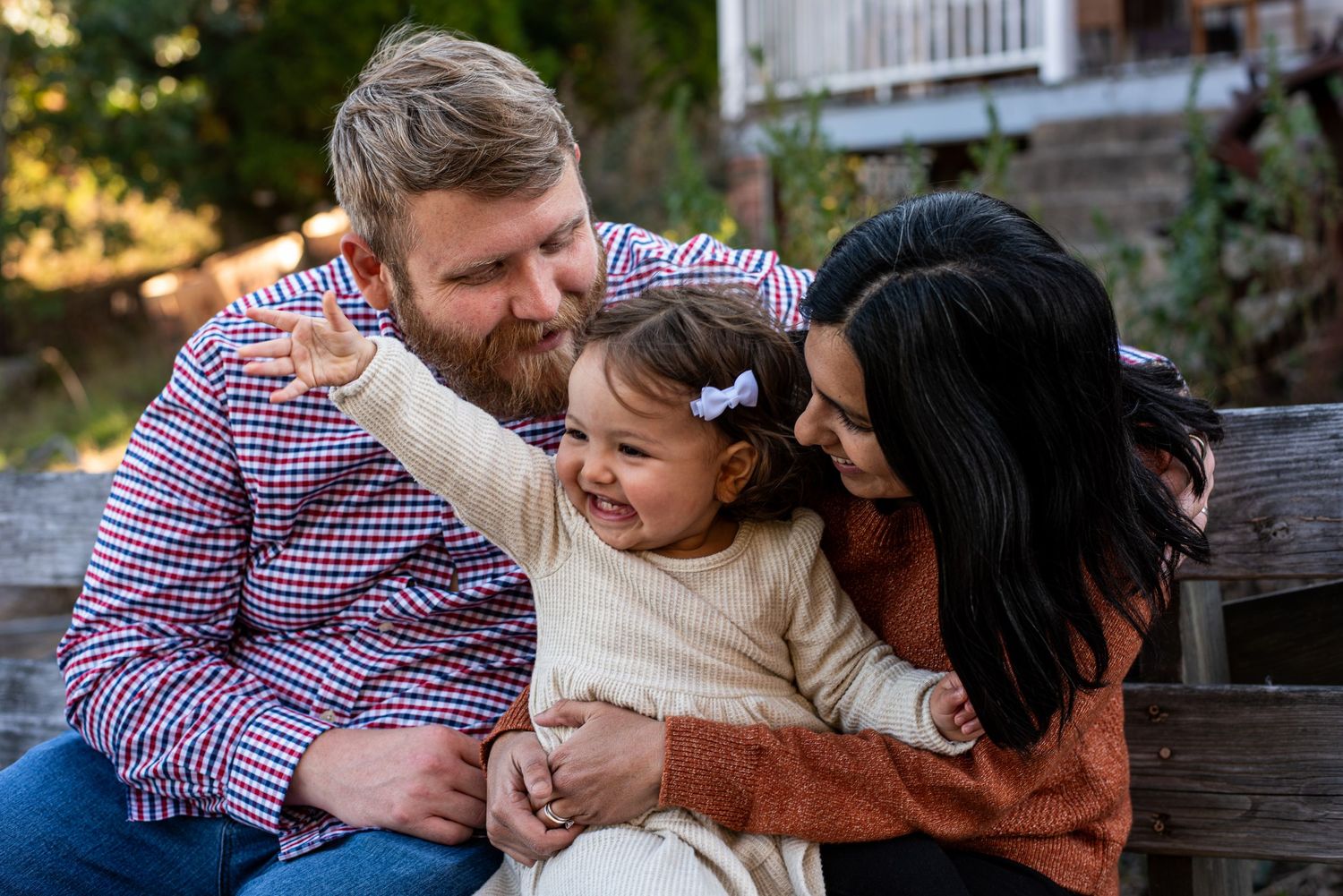 A cozy fall photo shoot with a black dog joining a maternity session in a natural outdoor setting.